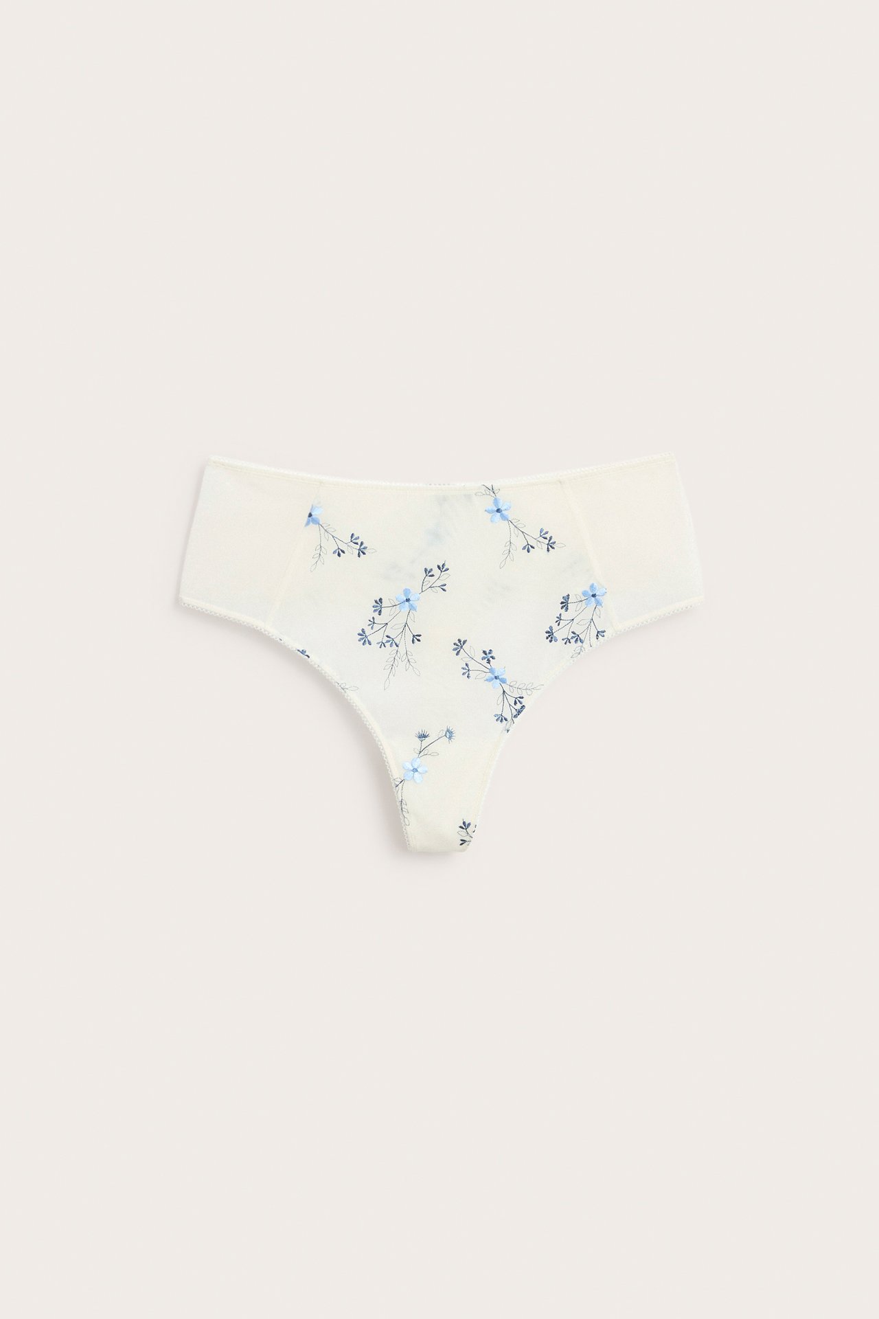 Edestä näkymä kermanvärisistä korkeavyötäröisistä mesh-stringeistä sinisellä kukkakirjonnalla ja picot-reunuksella.