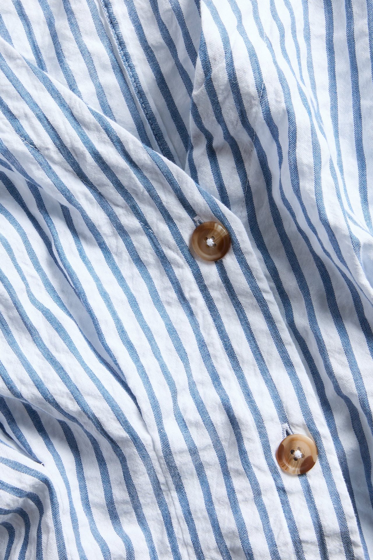 Lähikuva sinivalkoraidallisesta, bäckebölja-kuvioisesta midimekosta kahdella ruskealla napilla.