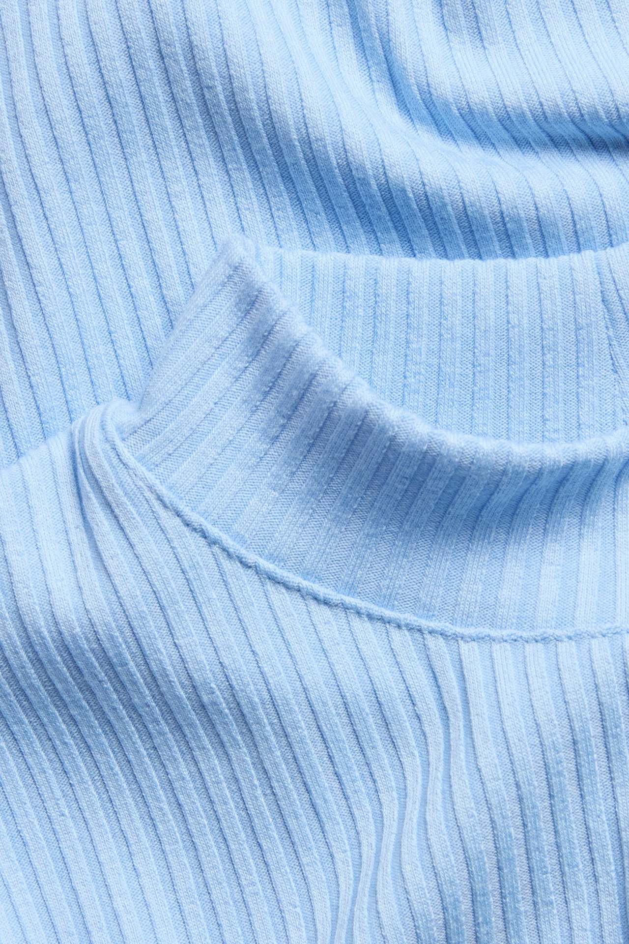 Zbliżenie jasnoniebieskiego, prążkowanego topu z kołnierzykiem polo.
