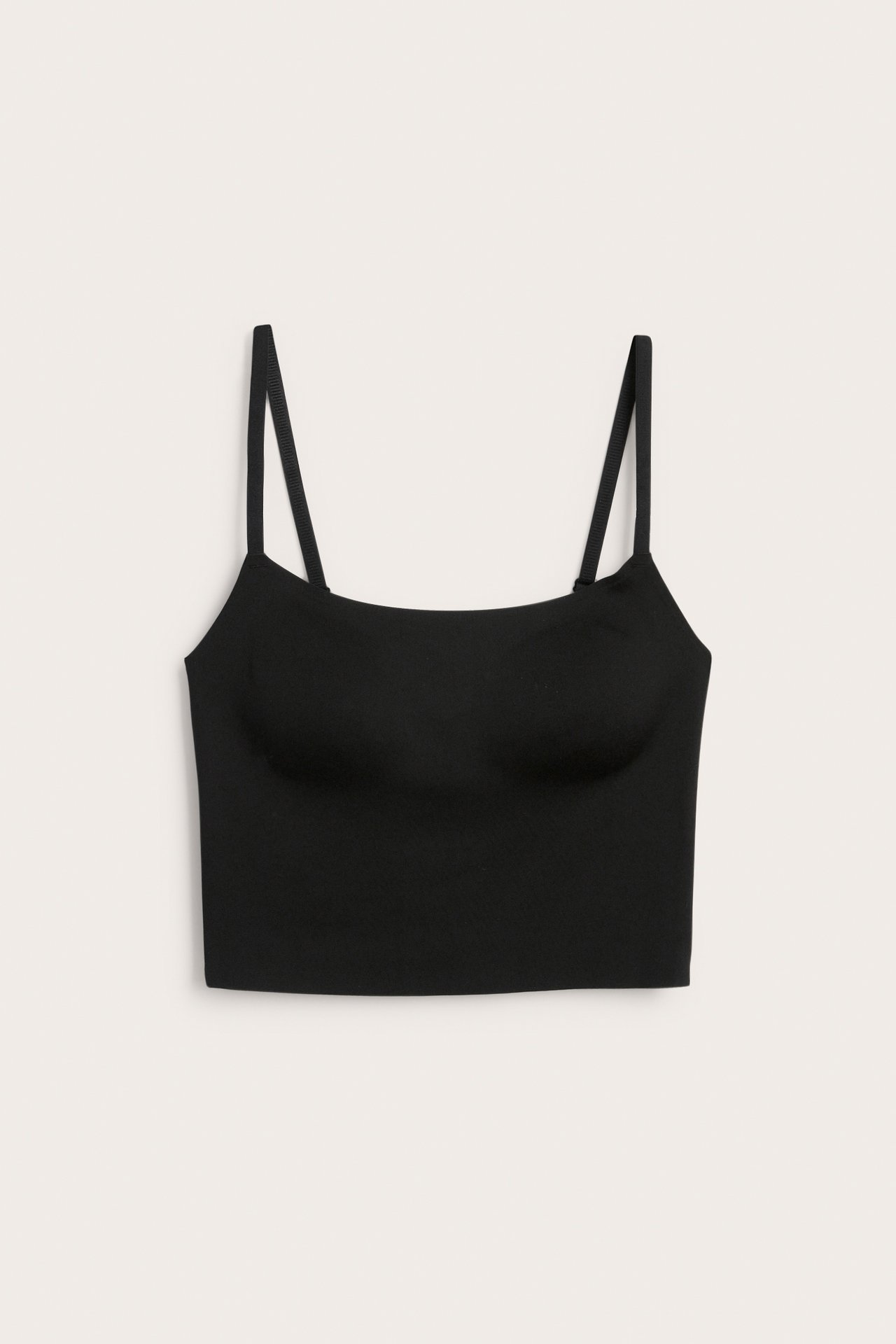 Framifrån, en svart sömlös, trådfri BH med smala justerbara axelband och en fyrkantig halslinning.