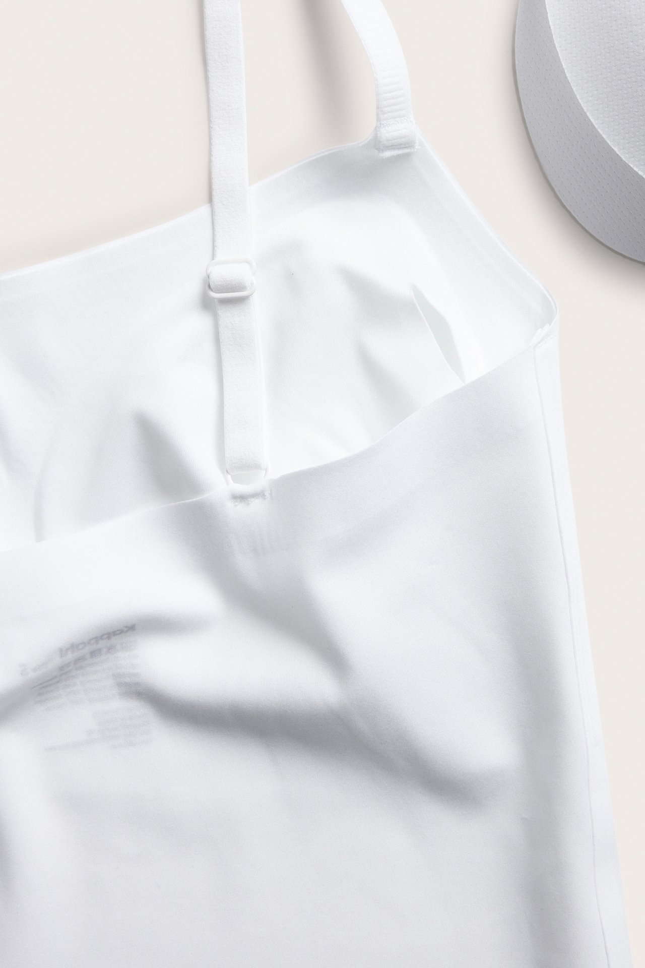 Närbild på en vit sömlös bralette med justerbara axelband och mjukt, stretchigt tyg.