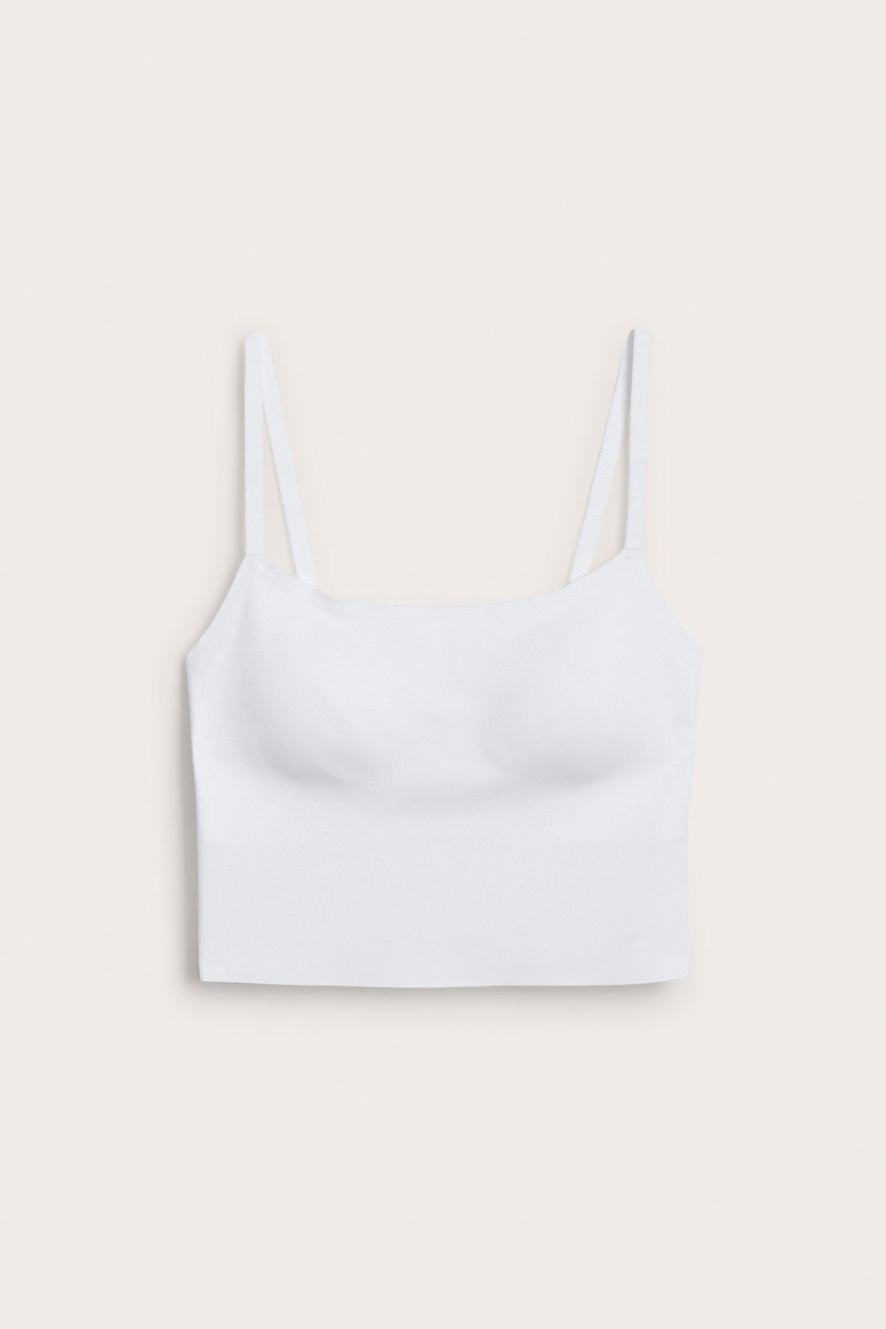 Framsida av en vit sömlös lång-bh i stretchigt mikrofiber med justerbara axelband.