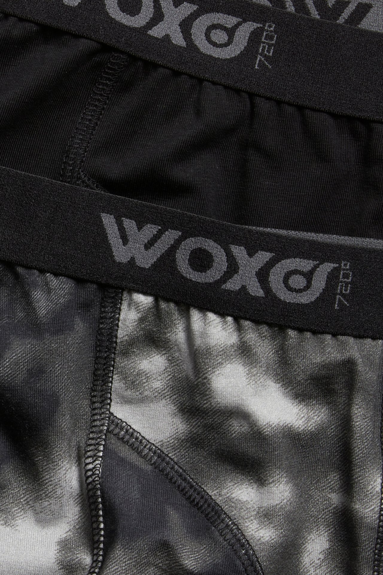 Lähikuva kahdesta lasten bokserista: yhdet yksiväriset mustat ja toiset musta-harmaakuvioiset, molemmissa musta kuminauha vyötäröllä.