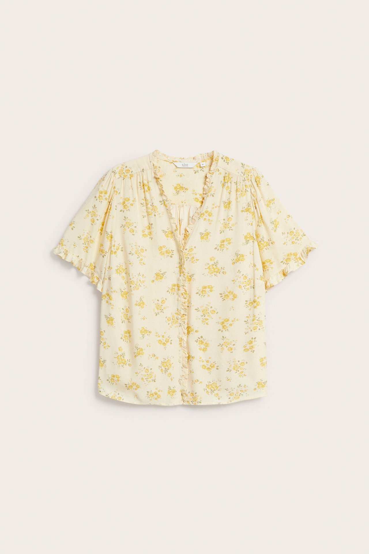 Widok z przodu jasnej, żółtej bluzki wiskozowej w kwiaty, z dekoltem w serek, falbankami i krytymi guzikami.