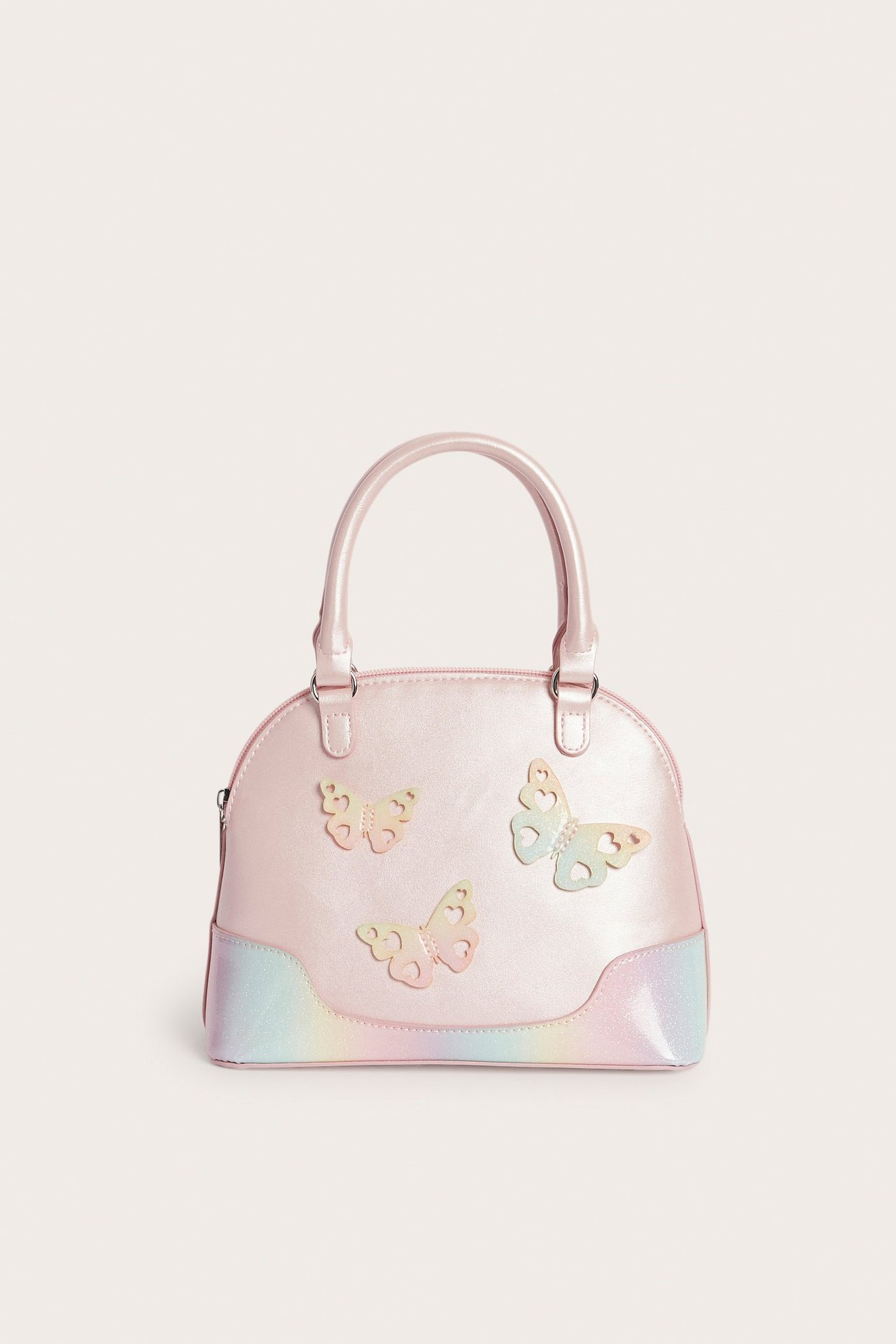 Edestä: Vaaleanpunainen kupolikäsilaukku sateenkaarisävyisellä pohjalla, perhosapplikaatioilla ja kahdella kahvalla.