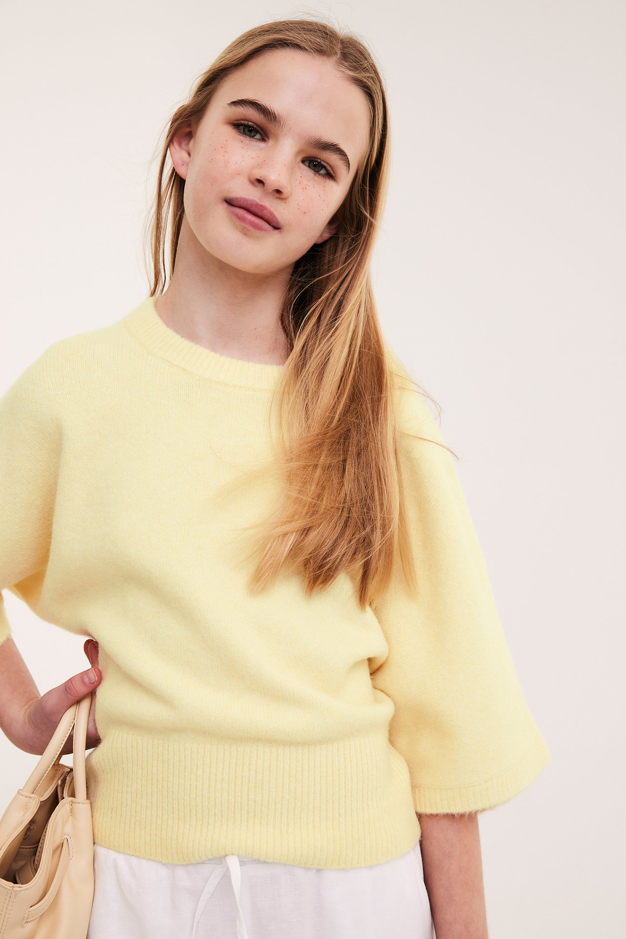 Dziewczynka w jasnobrązowym swetrze, jednolity kolor, krótkie rękawy, casual, front.