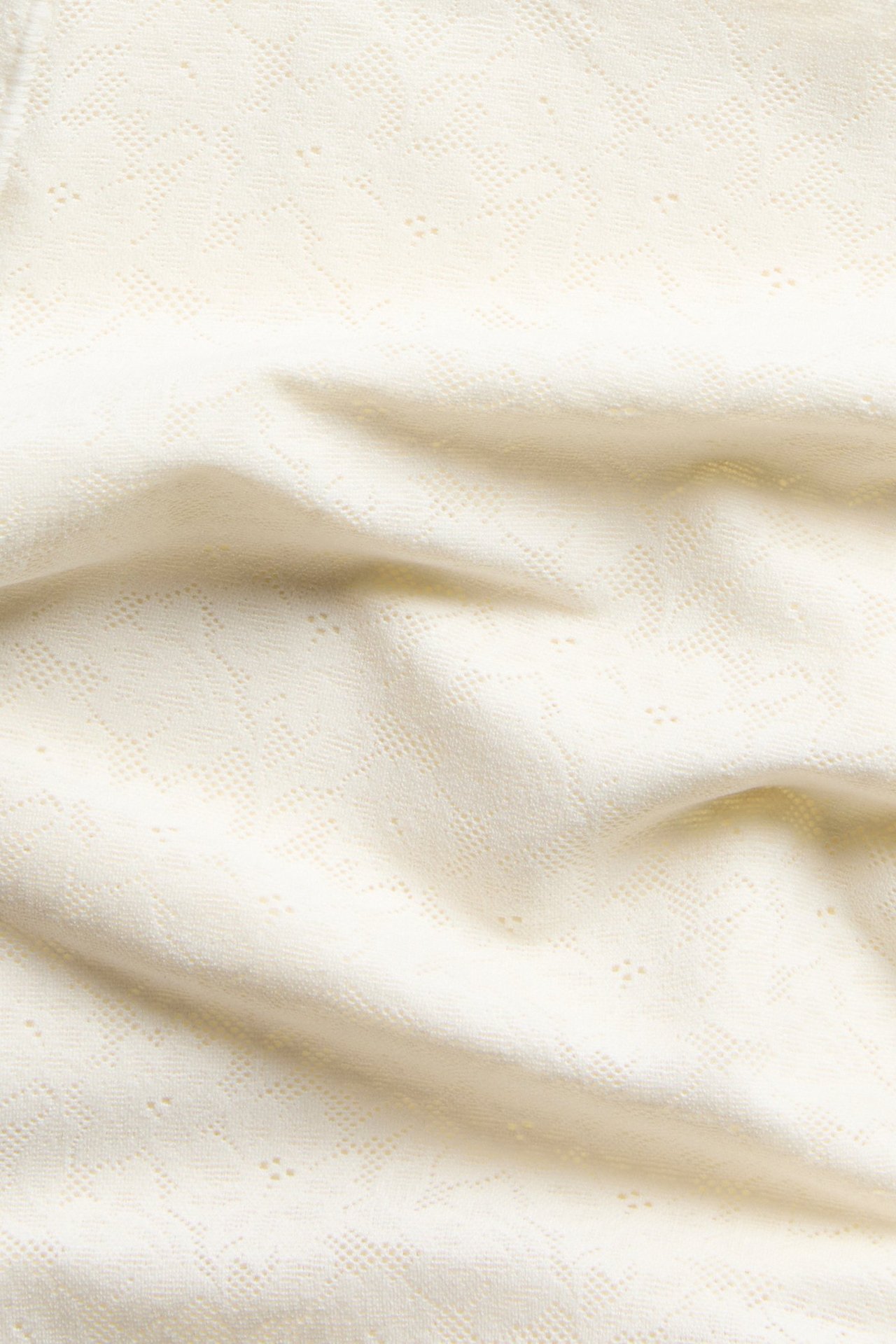 Närbild av naturvit stretchig spetsväv för shorts med hög midja.