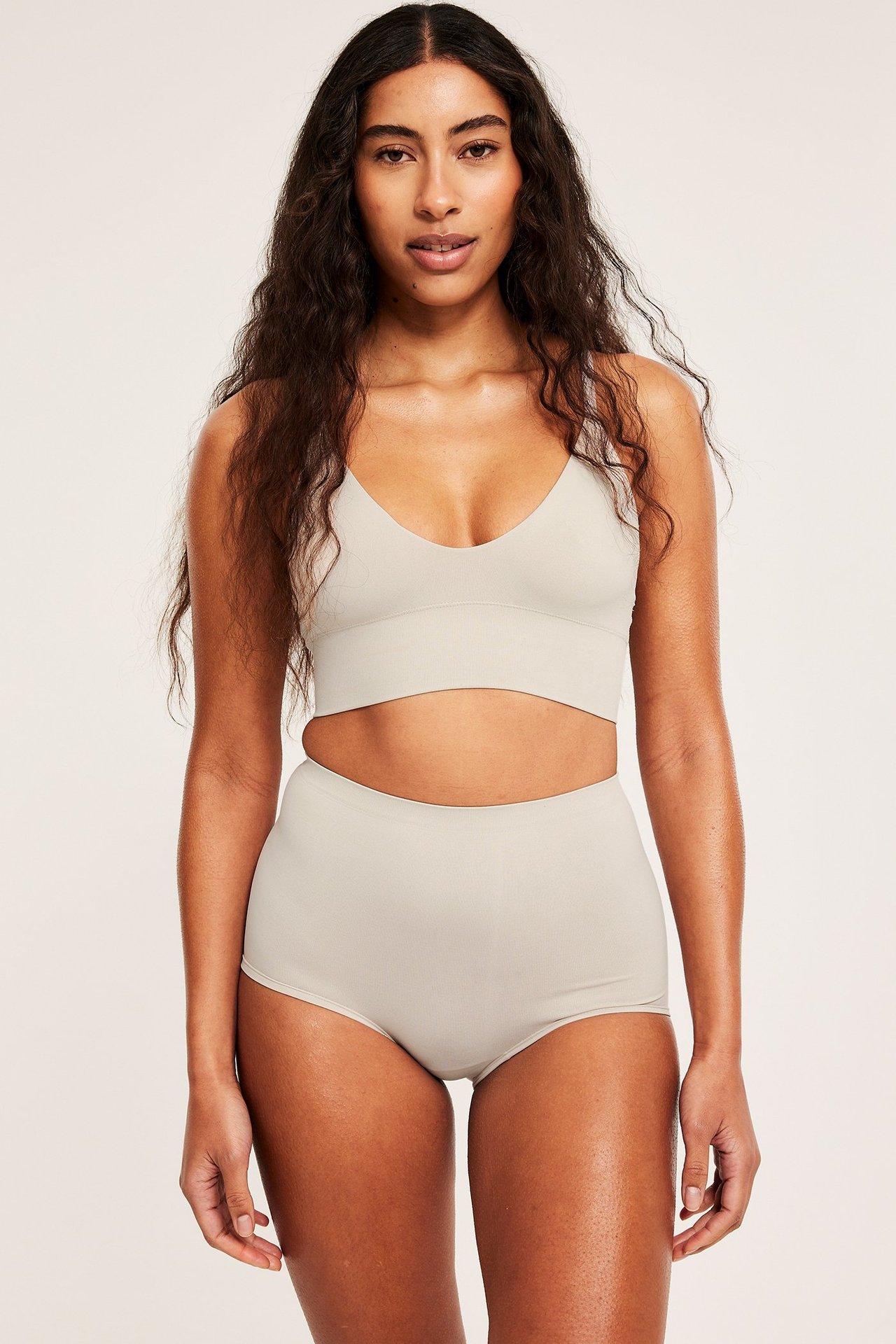 Framifrån, kvinna i offwhite sömlös bh och matchande högmidjade trosor.