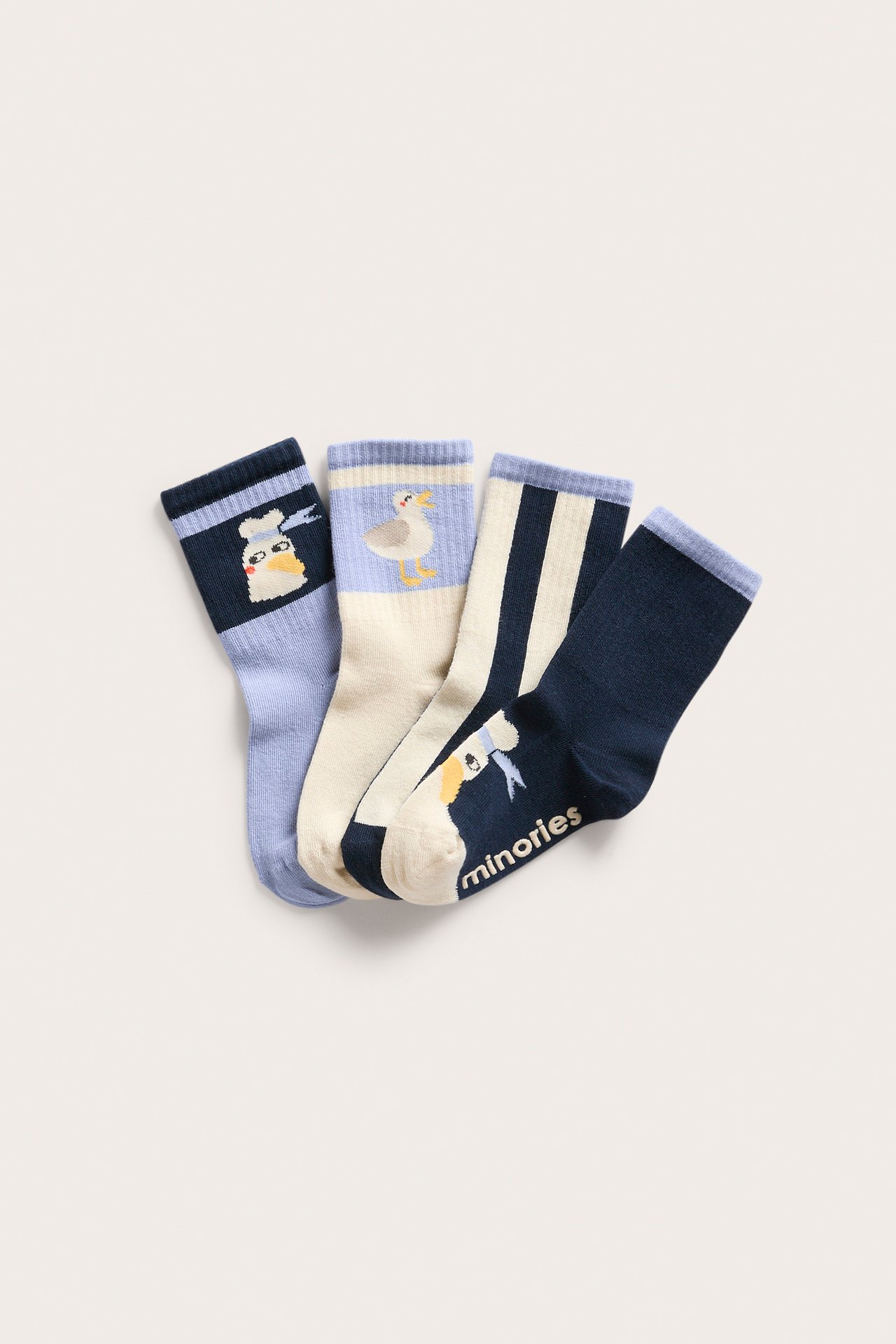 Ovanifrån: Fyra par mönstrade barnstrumpor i blått och gräddvitt med olika fågelmotiv och ränder.