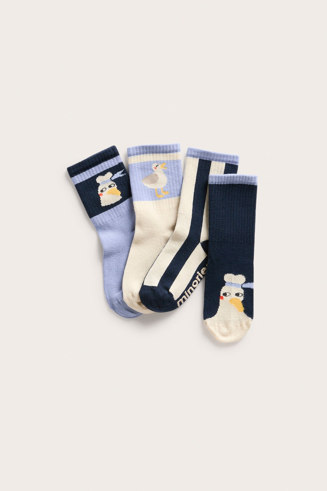 Framifrån, fyra par blå och vit/benvita barnstrumpor med olika fågel- och randmönster.