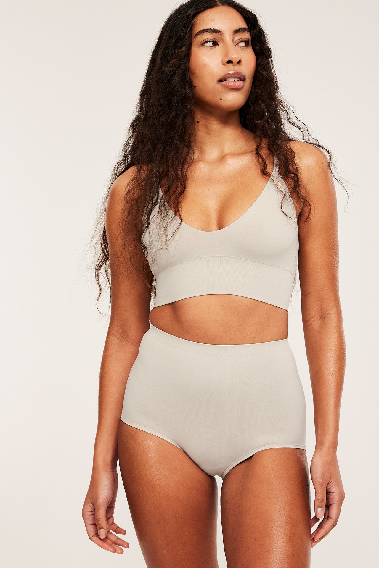 Framifrån: kvinna i sömlösa höga offwhite boxer trosor och matchande sömlös behå.