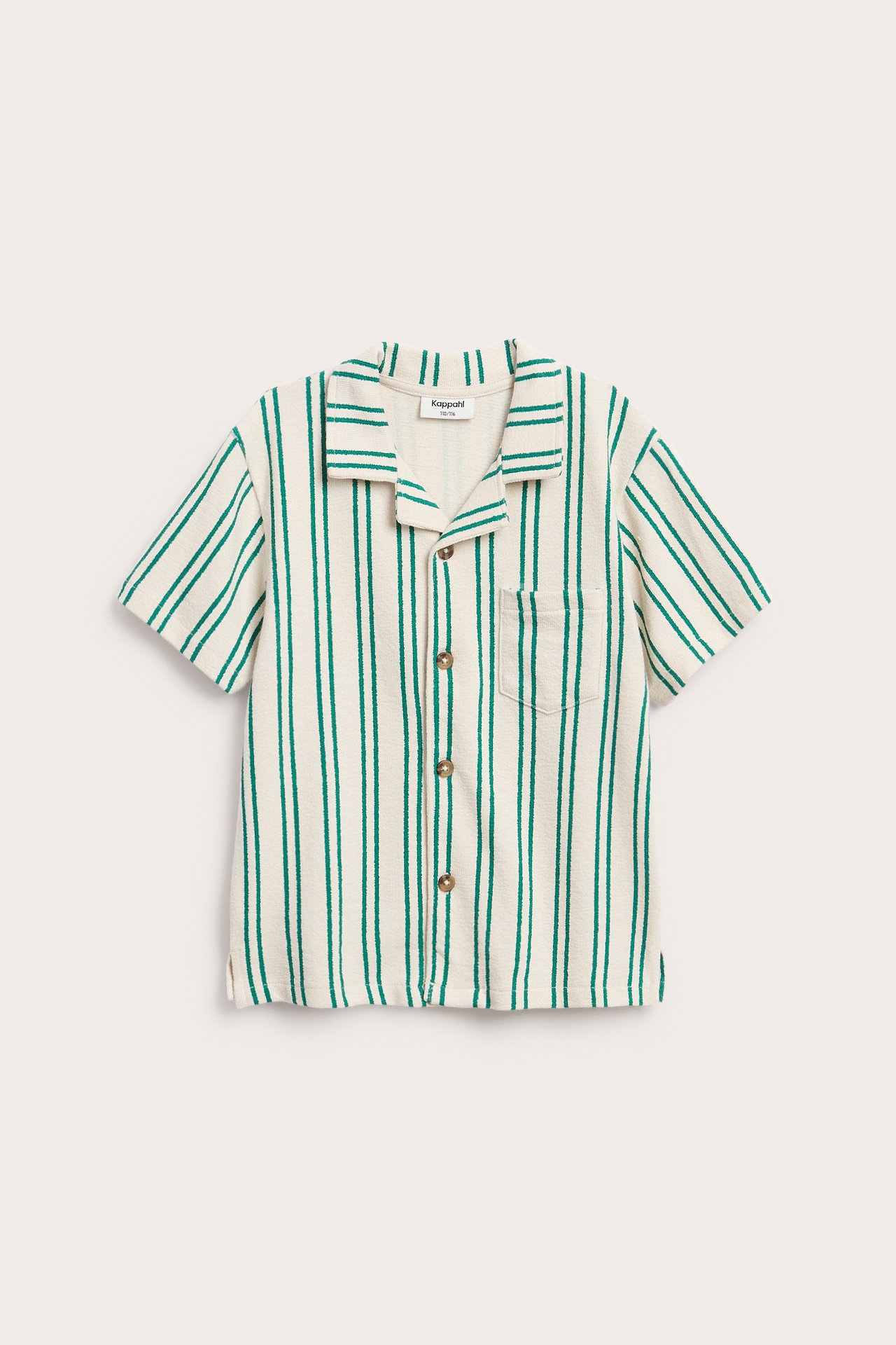 Framifrån: Gräddvit/grönrandig kortärmad barnskjorta i bomullstrikå med lös passform, knappar, ficka.