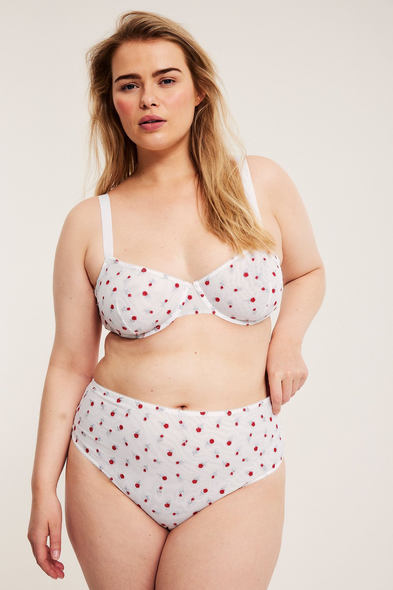 Widok z przodu kobiety w off-white figach z siateczki i pasującym biustonoszu z czerwonym wzorem jagód.