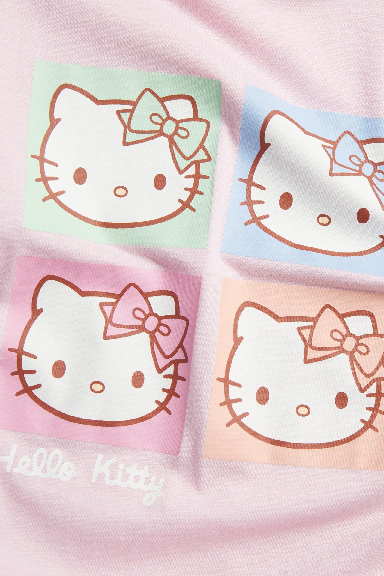 Närbild av en rosa bomulls-T-shirt med ett färgglatt Hello Kitty-tryck framtill.