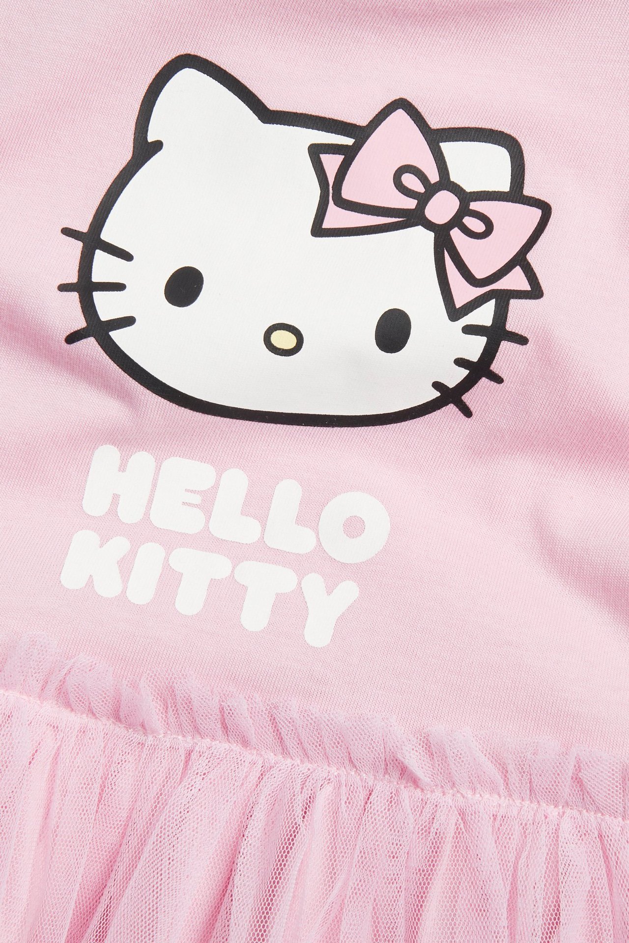 Lähikuva vaaleanpunaisesta lasten trikoomekosta, jossa Hello Kitty -printti ja vaaleanpunainen verkkohame.