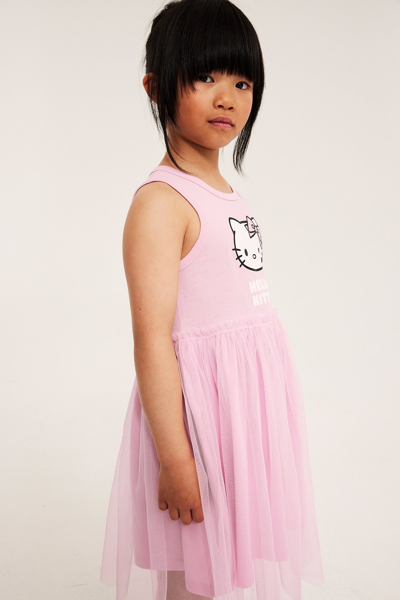 Etusivukuva lapsesta vaaleanpunaisessa hihattomassa Hello Kitty trikoomekossa, jossa tyllihame.