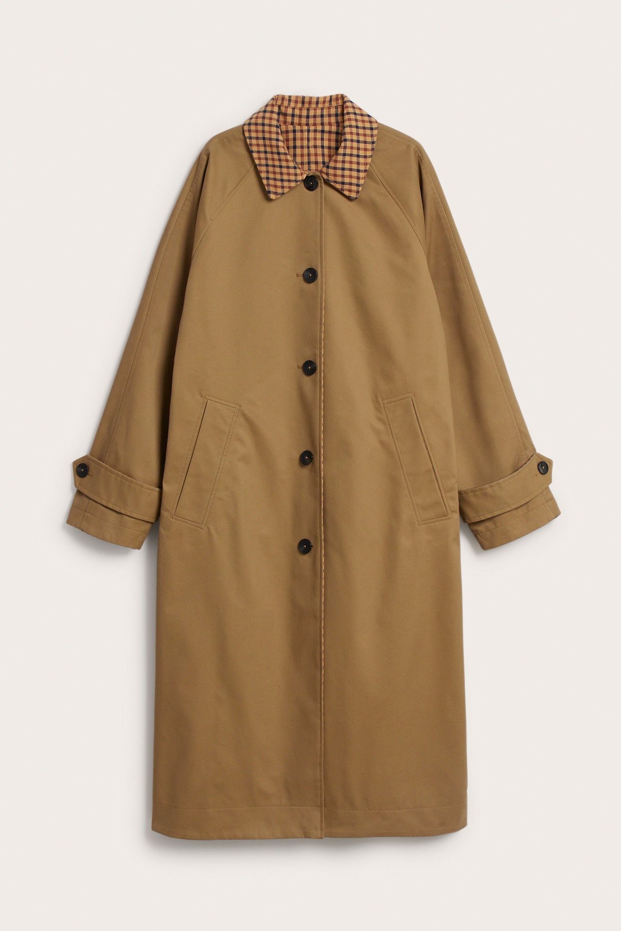 Framifrån: Lång beige vändbar trenchcoat med rutig krage, knäppning fram och framfickor.
