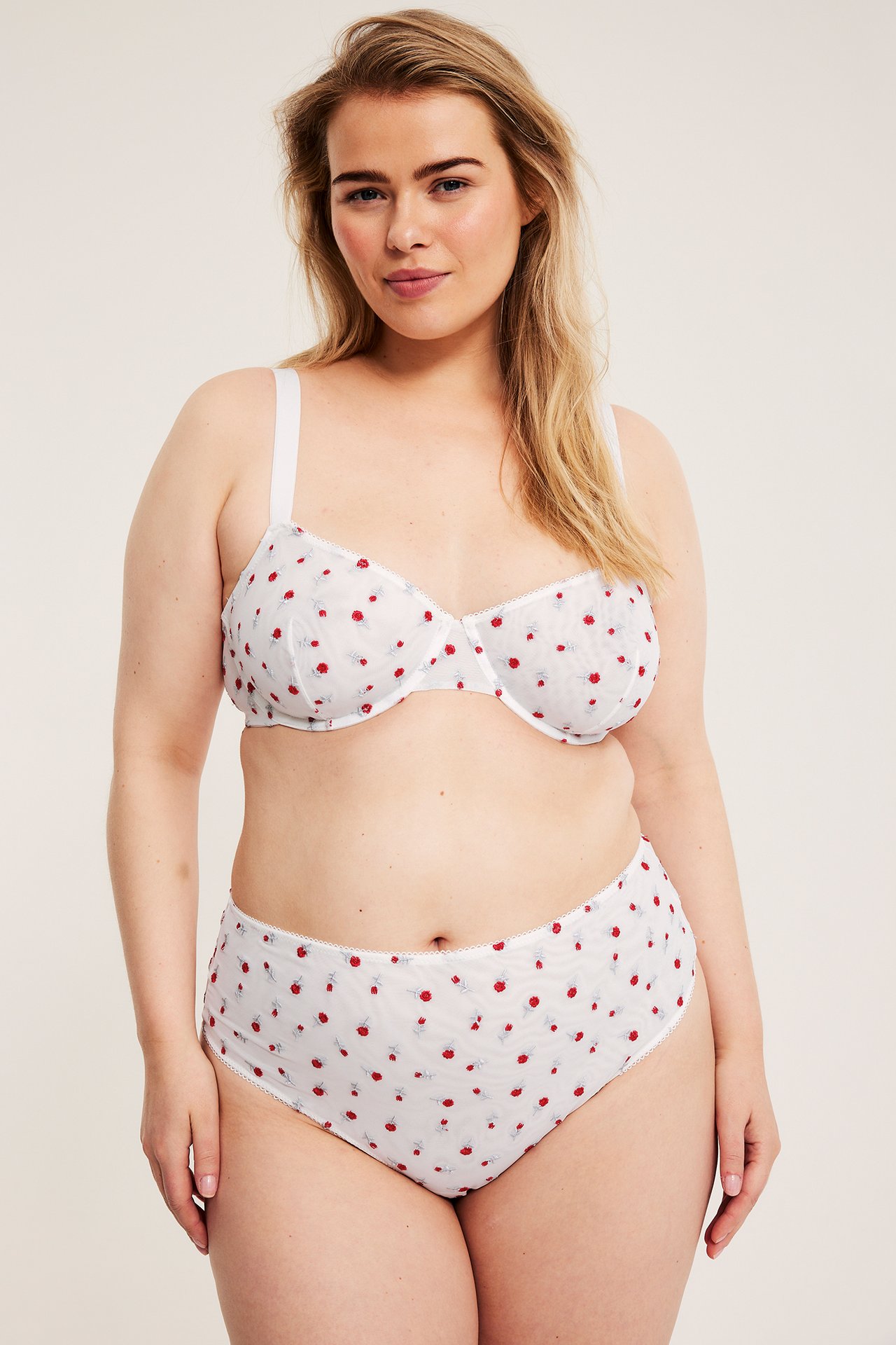 Forfra: Kvinne i off-white mesh bøyle-BH med rød rosebroderi og matchende truse.