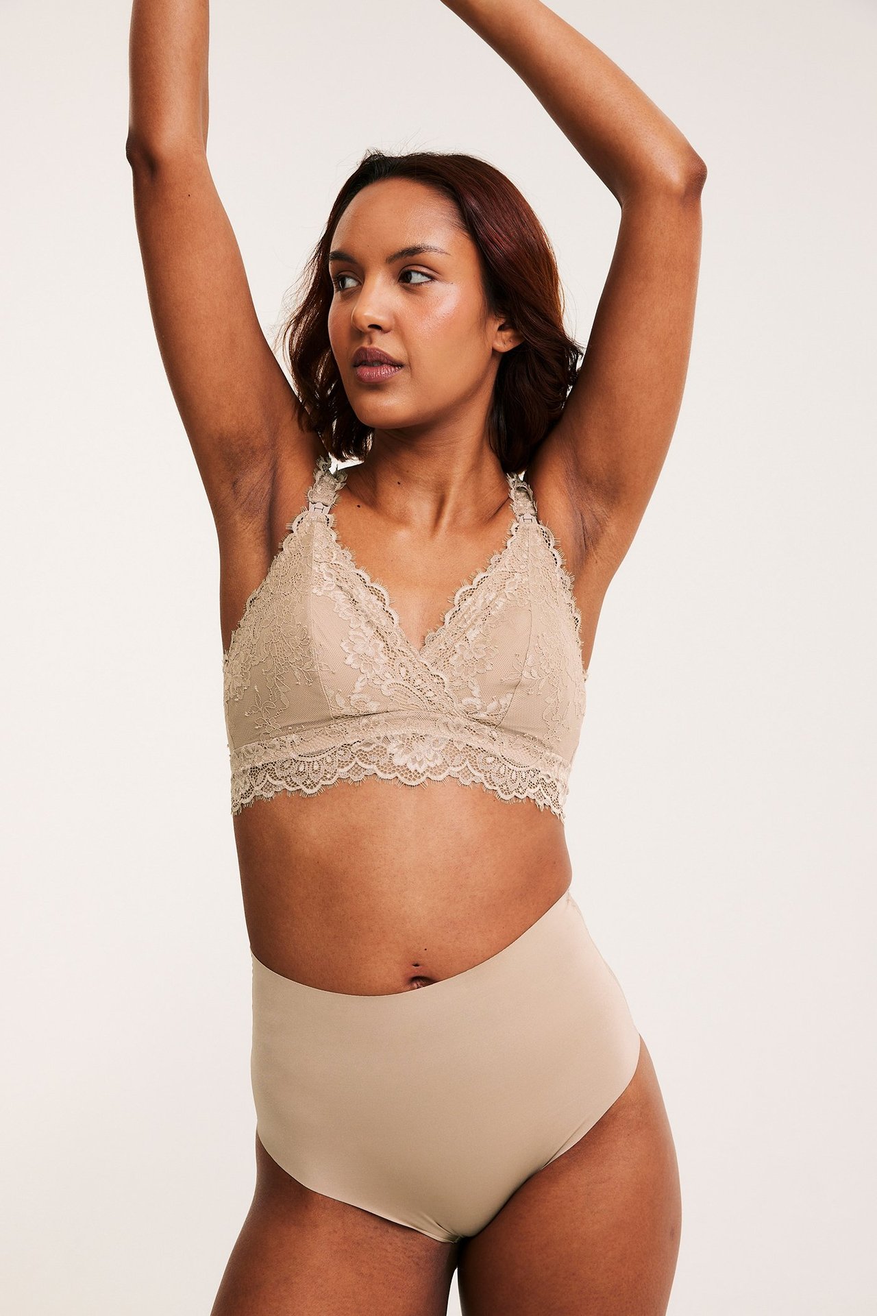 Edestäpäin, nainen yllään ruskeat saumattomat korkeavyötäröiset alushousut ja yhteensopivat pitsiliivit.