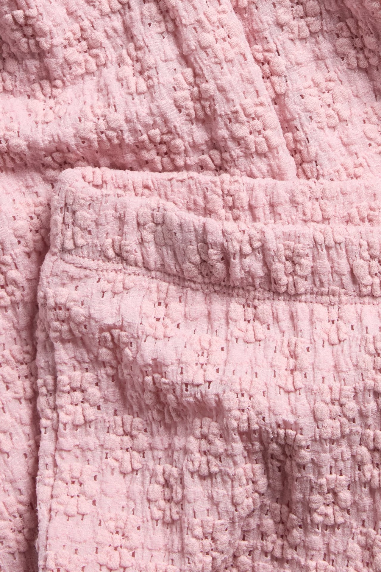 Zbliżenie jasnoróżowych rozszerzanych koronkowych legginsów z elastycznym pasem.