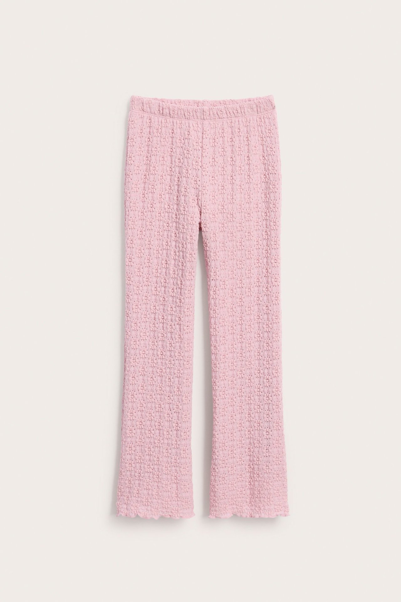 Widok z przodu: Jasnoróżowe rozszerzane koronkowe legginsy z gumką w pasie i obszyciem babylock.