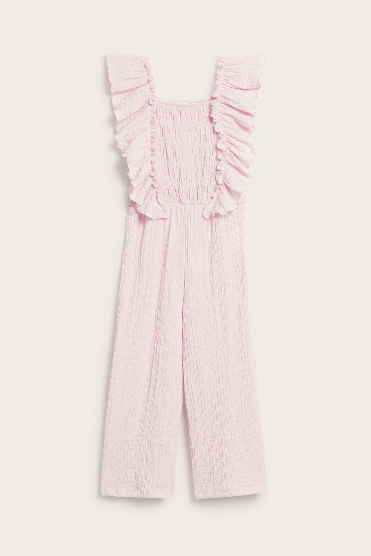 Frontutsikt: Lys rosa barnedress i strukturert jersey med skulderfløyelskanter, smockmidje og cropped ben.