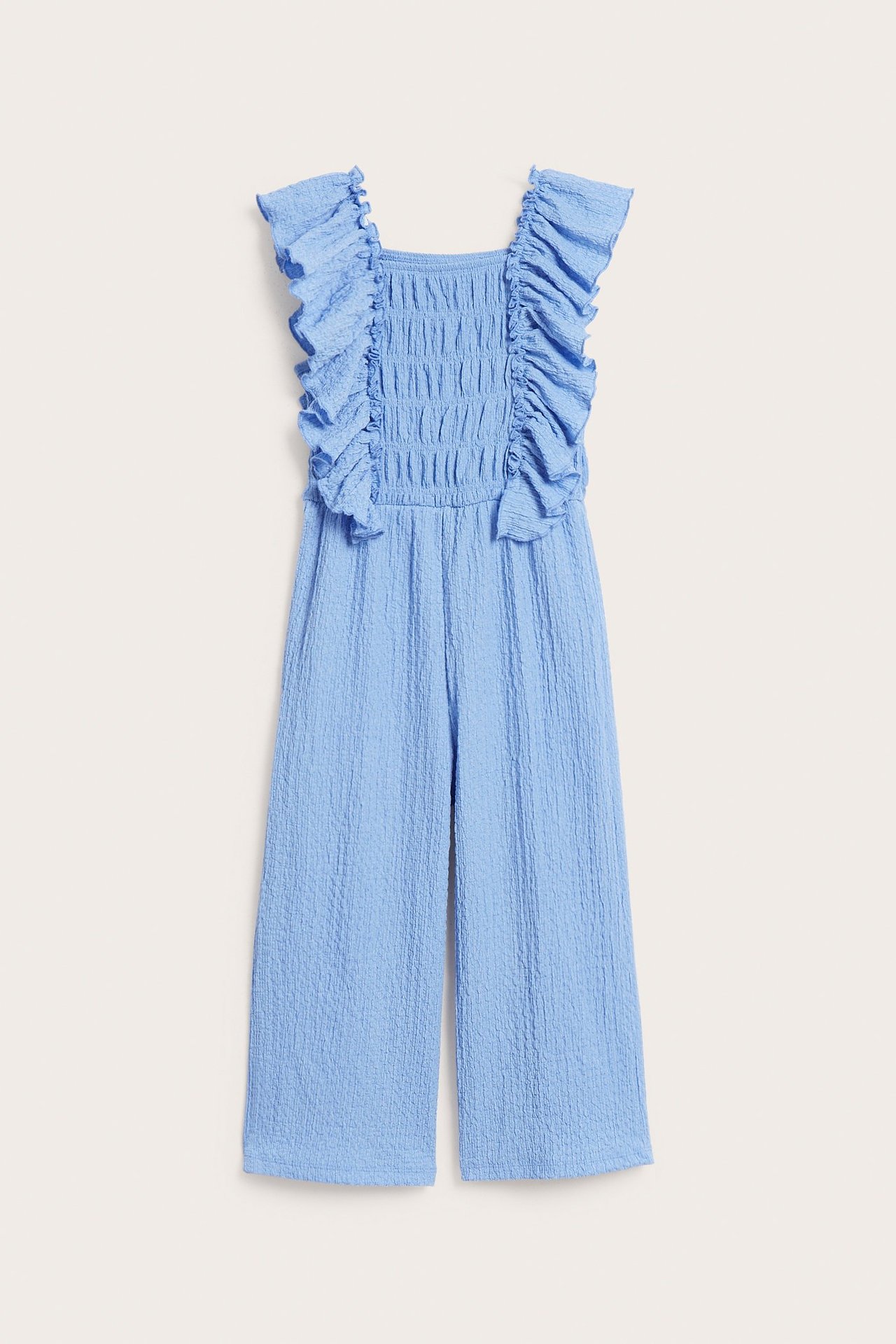 Lasten sininen jersey-haalaripuku, jossa on smokki vyötäröllä ja röyhelöt olkapäillä, edestä.