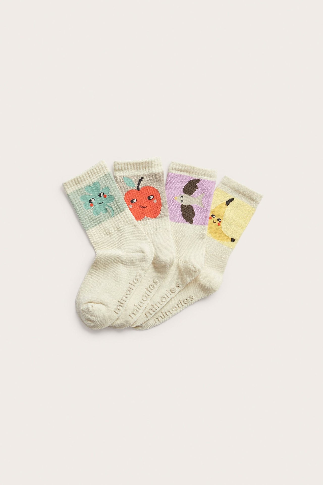 Ylhäältä neljä beigenväristä lastensukkaa hedelmä-, vihannes- ja lintukuvioilla.