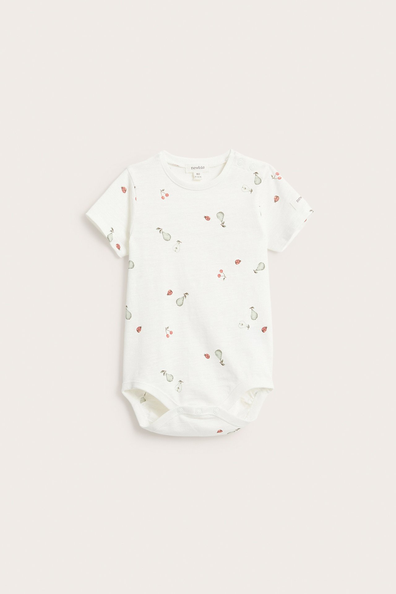Etunäkymä luonnonvalkoisesta lyhythihaisesta vauvan puuvillabodysta päärynä-, kirsikka- ja leppäkerttukuviolla.