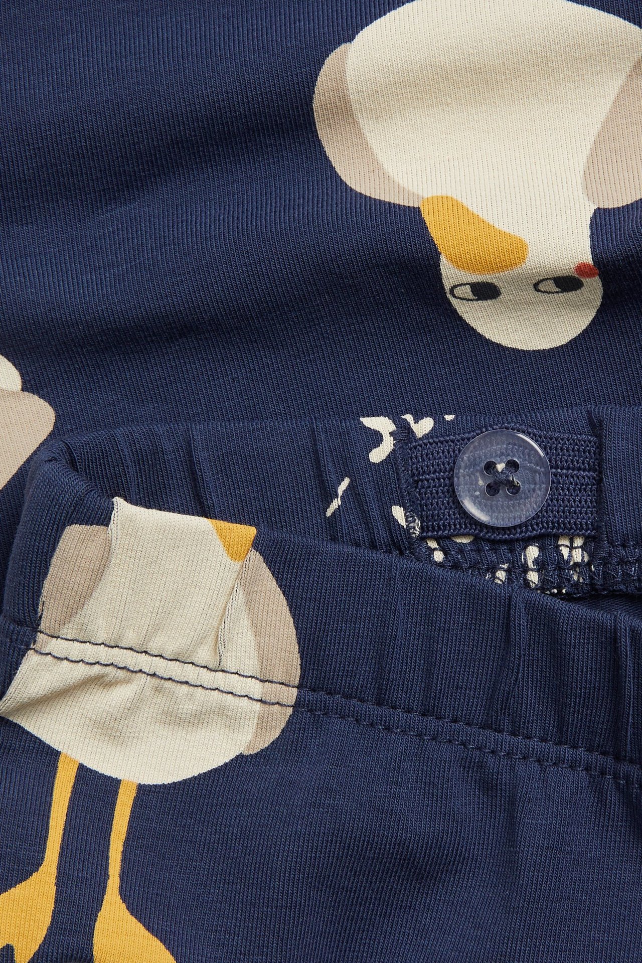 Närbild av barnens blåa cykelbyxor med ankmönster och justerbar resår i midjan med knapp.