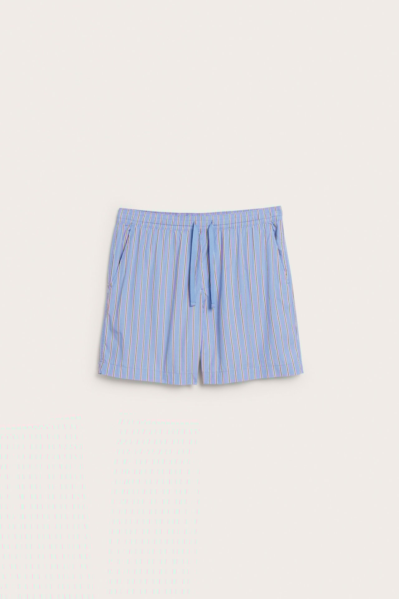 Framsida av herrshorts i blå bomullspoplin med vita och röda ränder, elastisk dragskomidja, samt fickor.