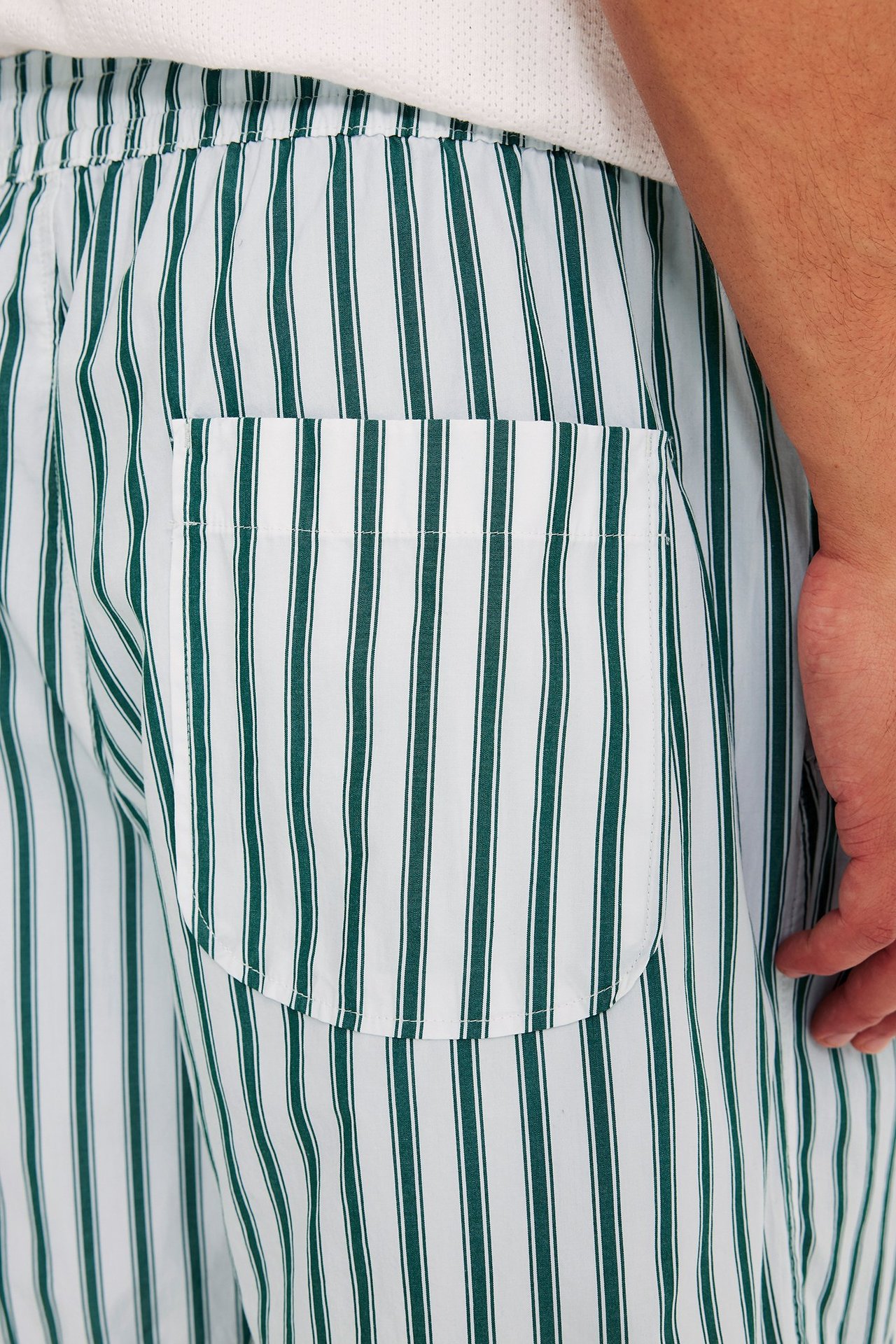 Nærbilde av hvite og mørkegrønne stripete bomullspoplinshorts for menn med elastisk midje og en lapplomme.