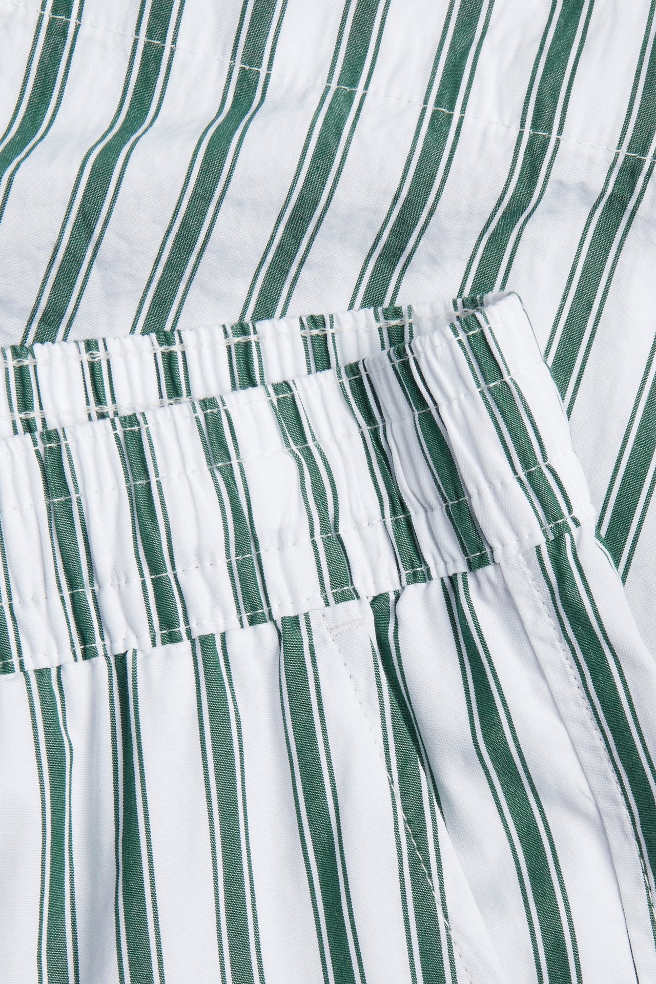 Nærbilde av hvite og grønne stripete bomullspoplinshorts med elastisk linning.