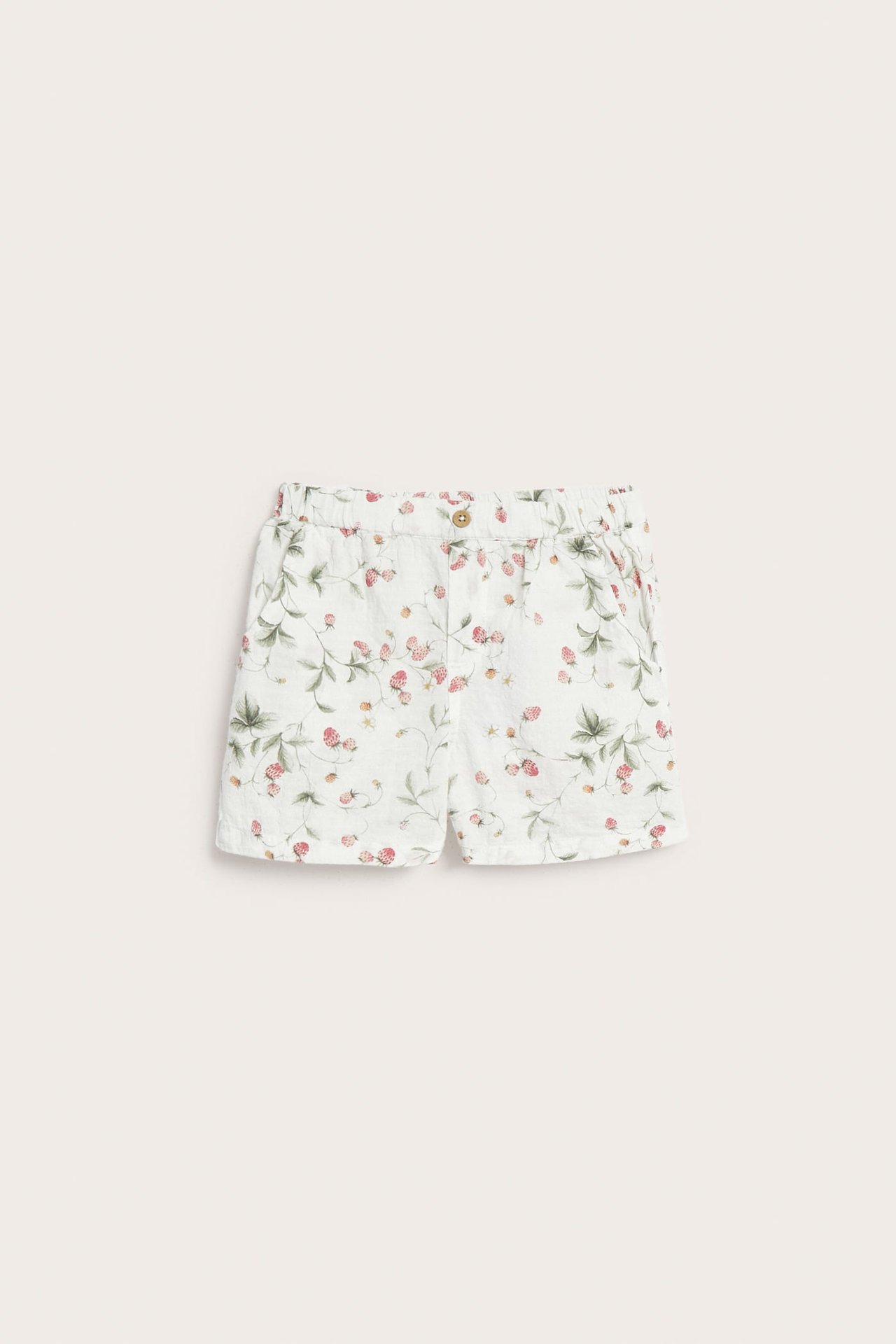 Frontvy av offwhite vävda bomullsshorts med jordgubbsmönster, resår i midjan och dekorativ knapp.