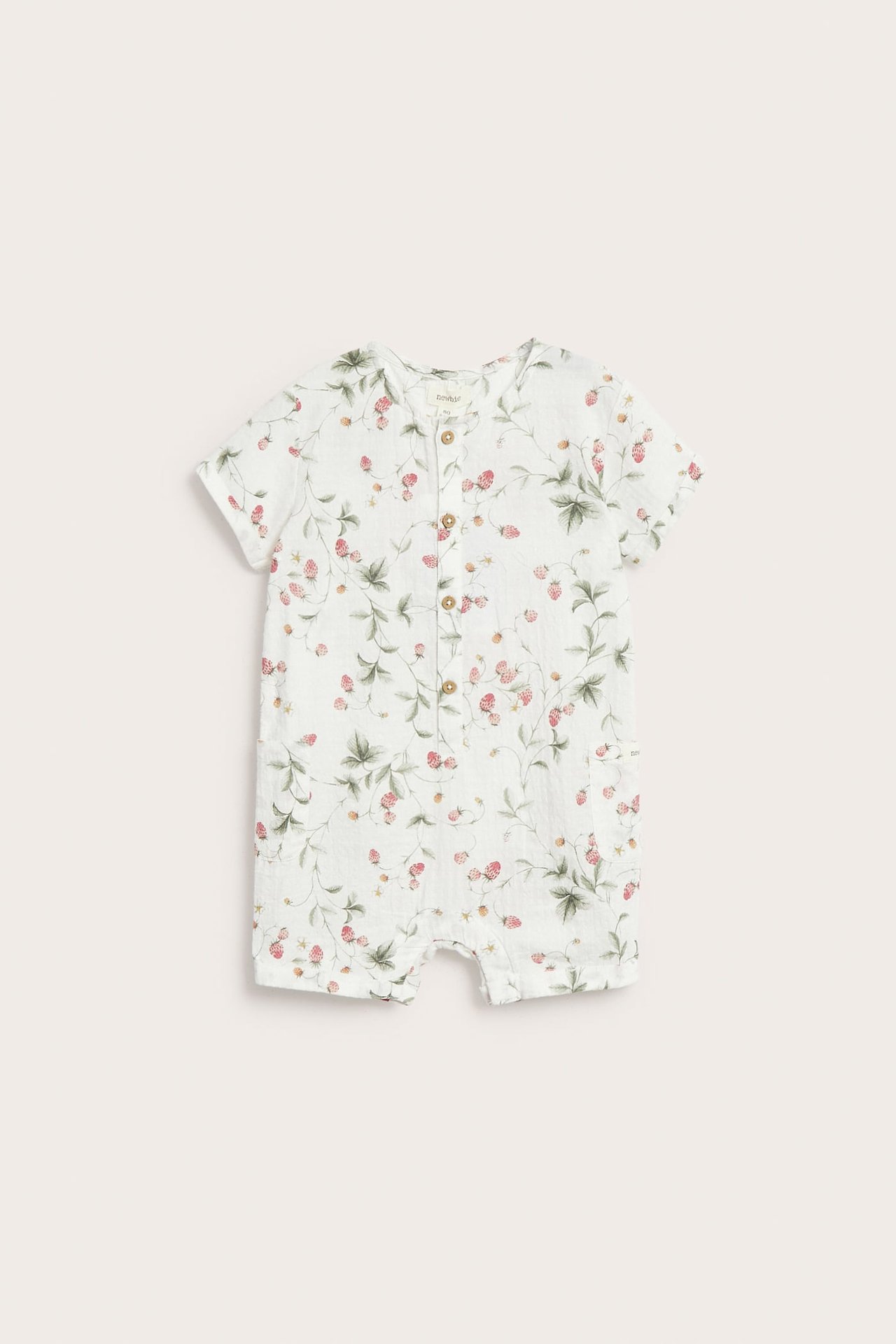 Framsida på en offwhite vävd babyromper i bomull med smultronmönster och träknappar fram.