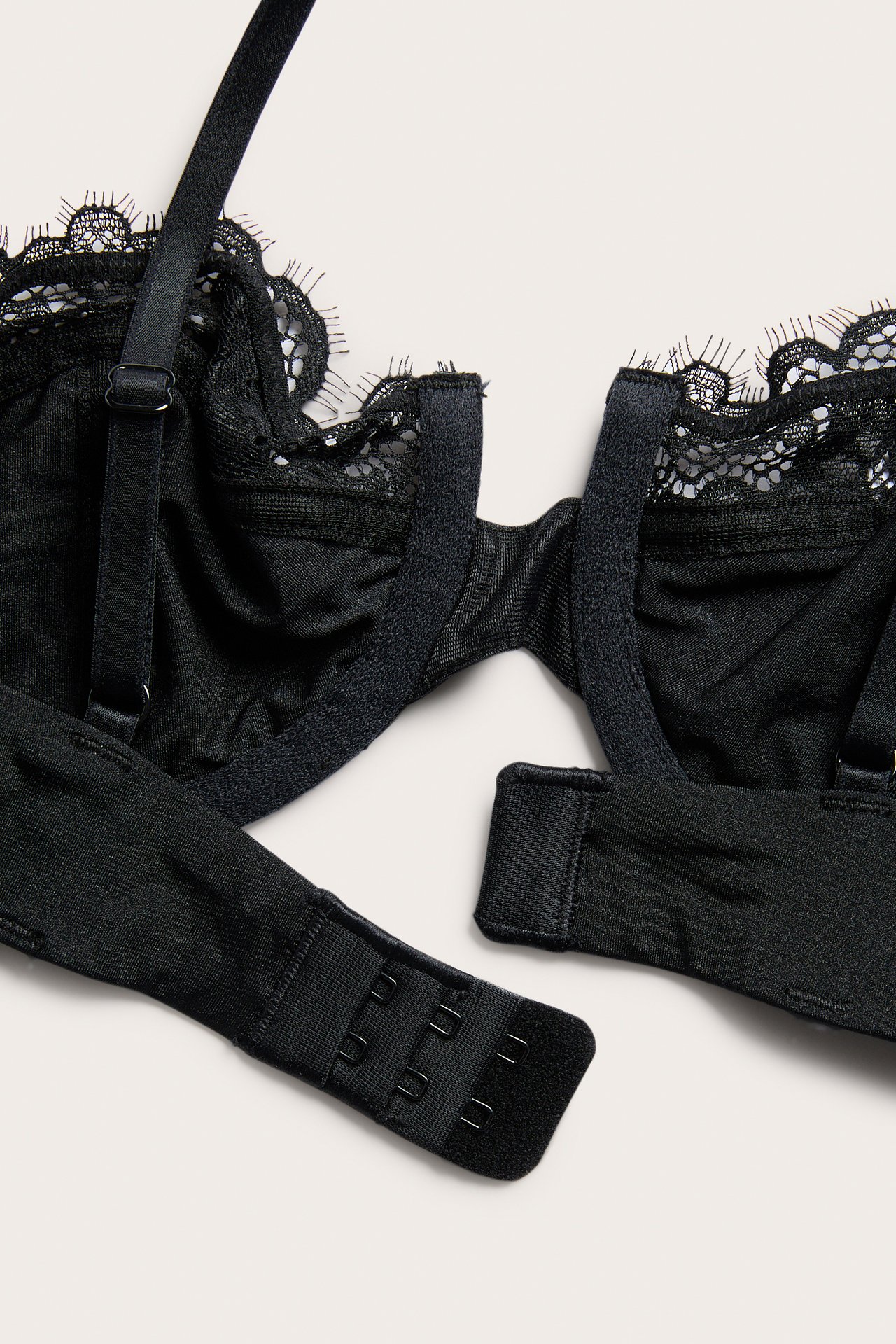 Zbliżenie czarnego koronkowego biustonosza typu balconette z regulowanymi ramiączkami i zapięciem z tyłu.
