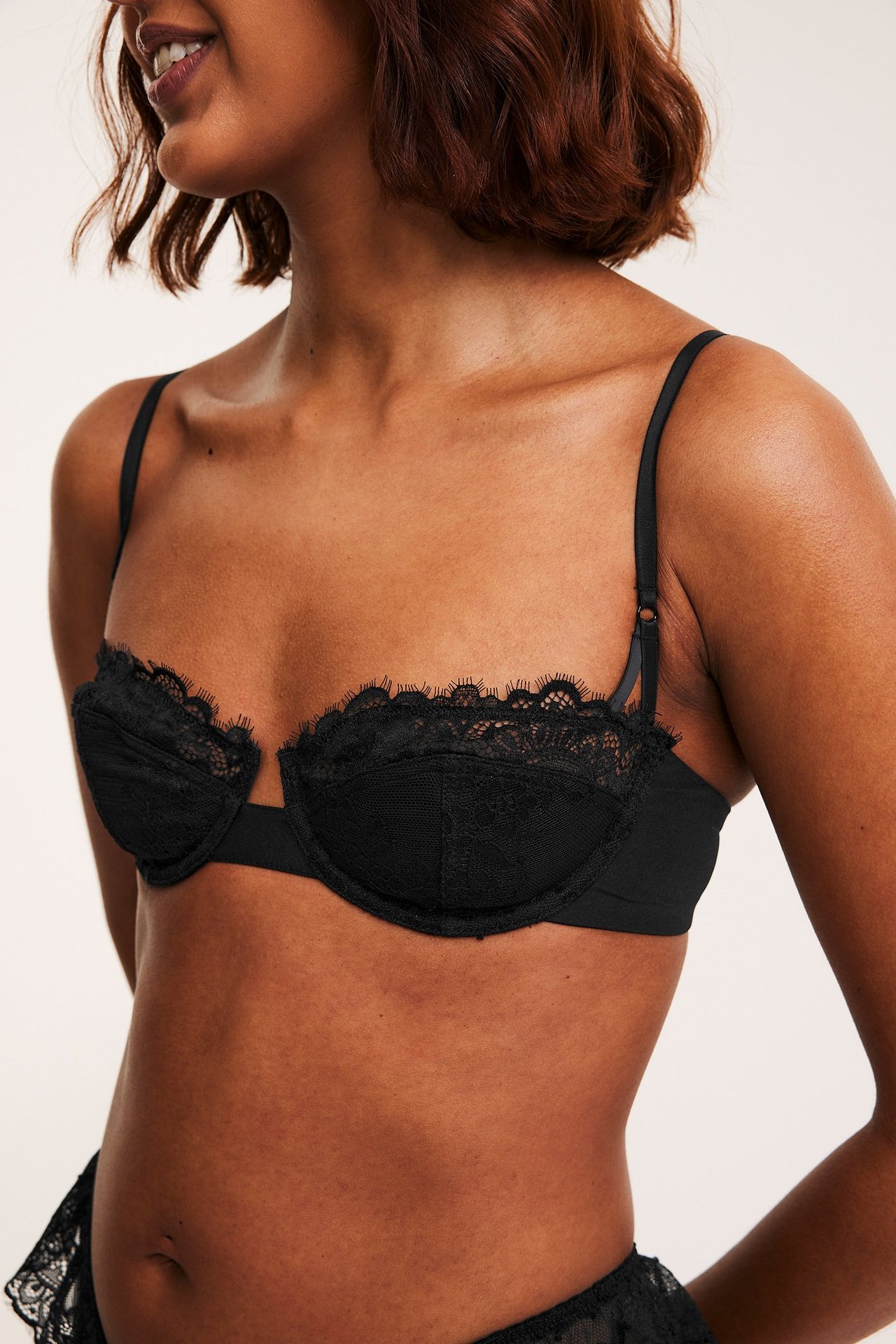 Nærbilde av kvinne i svart blonde balconette-BH med fine kanter og matchende blondeundertøy.