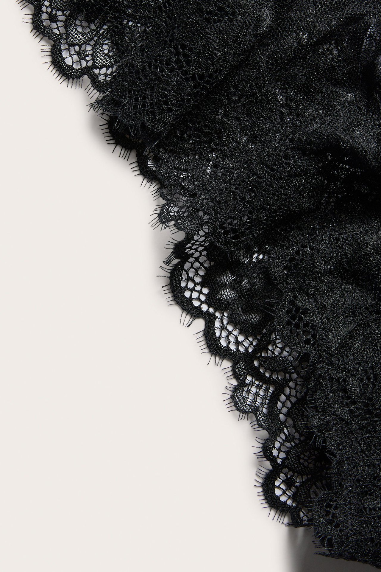 Närbild av svarta spets-cheeky trosor med vågiga kanter.