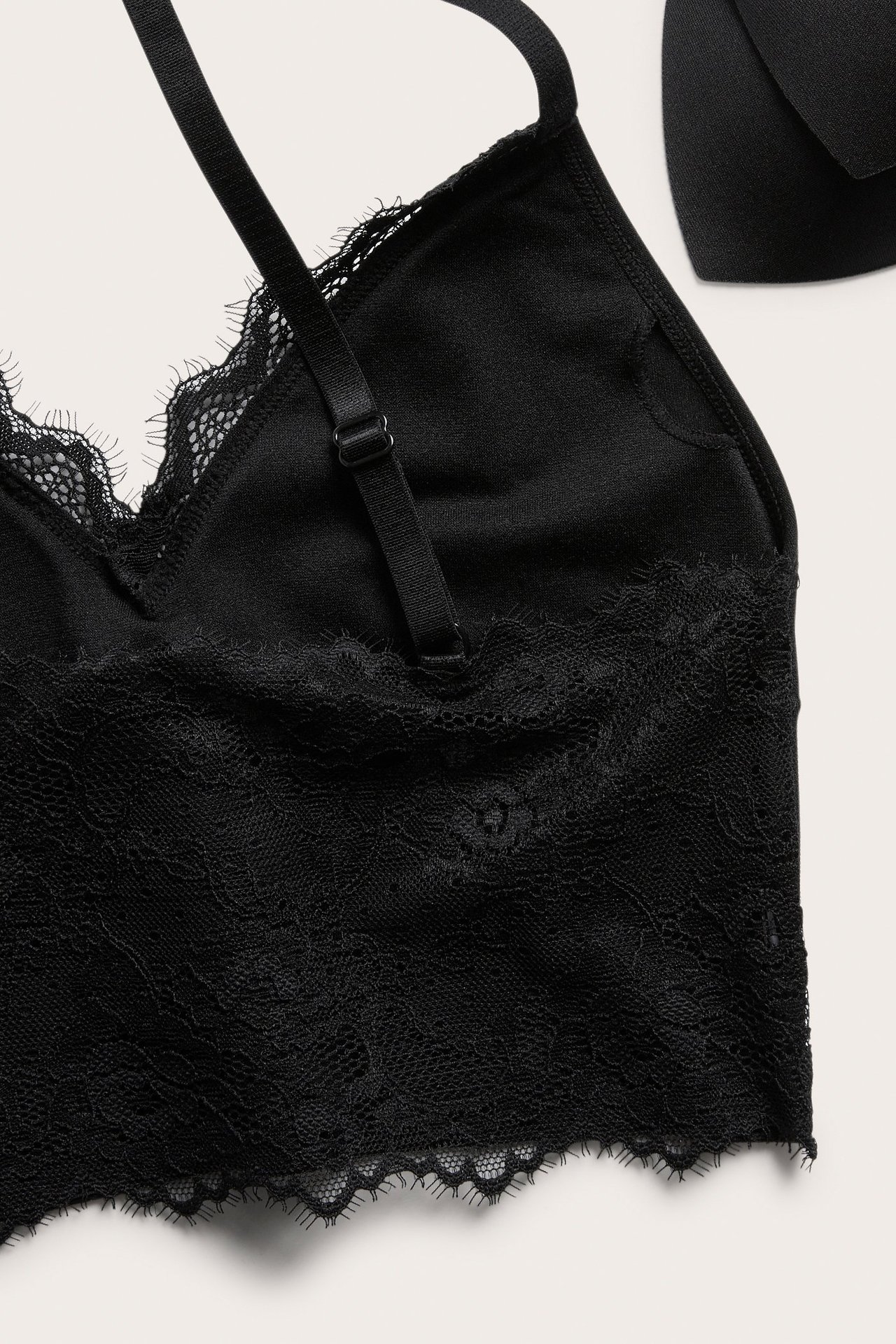 Widok z góry, zbliżenie na czarny biustonosz bez fiszbin z delikatną koronką przy miseczkach i pod biustem.