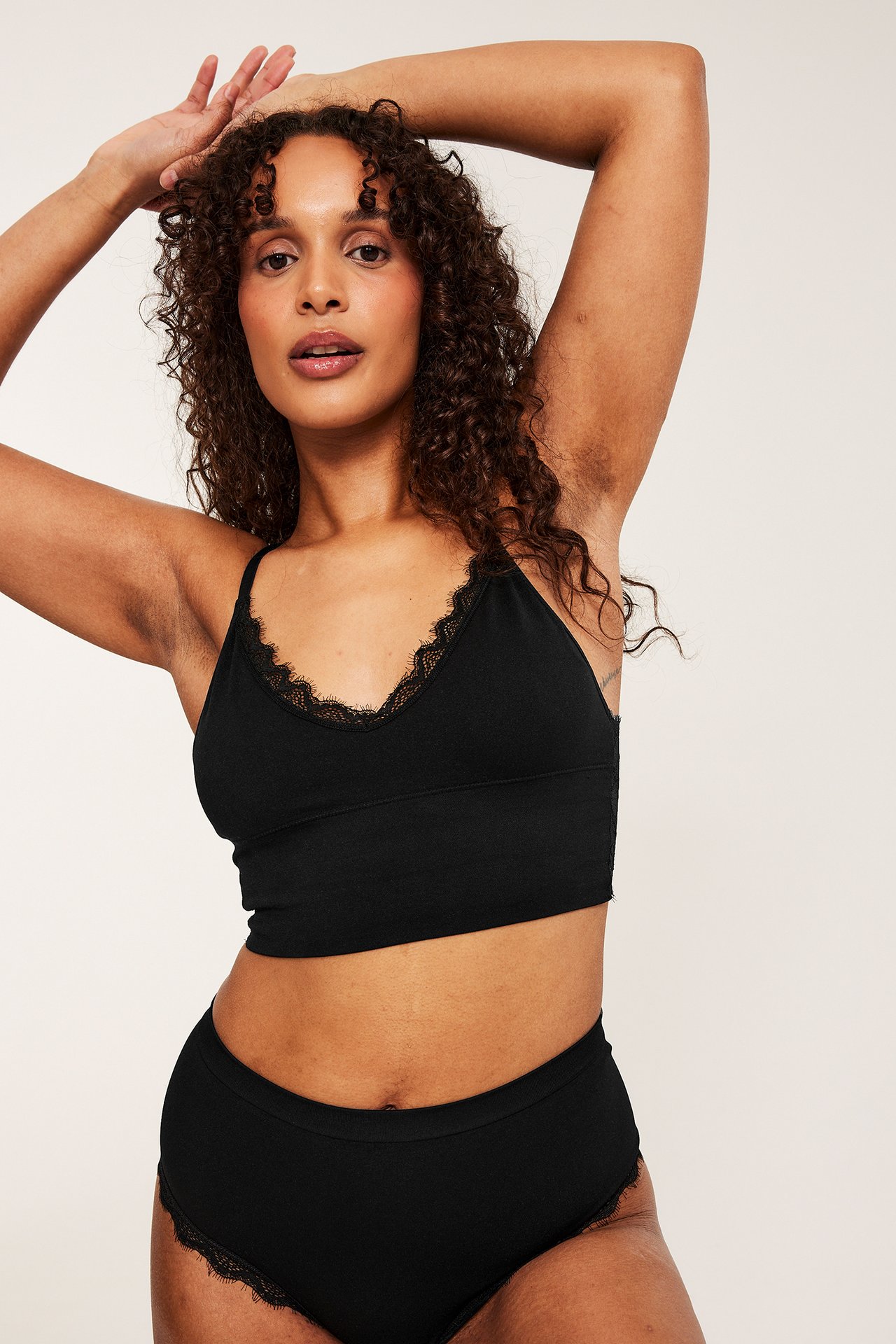 Frontbilde av en kvinne iført svart bøylefri BH med blonder og matchende høytlivstruser.