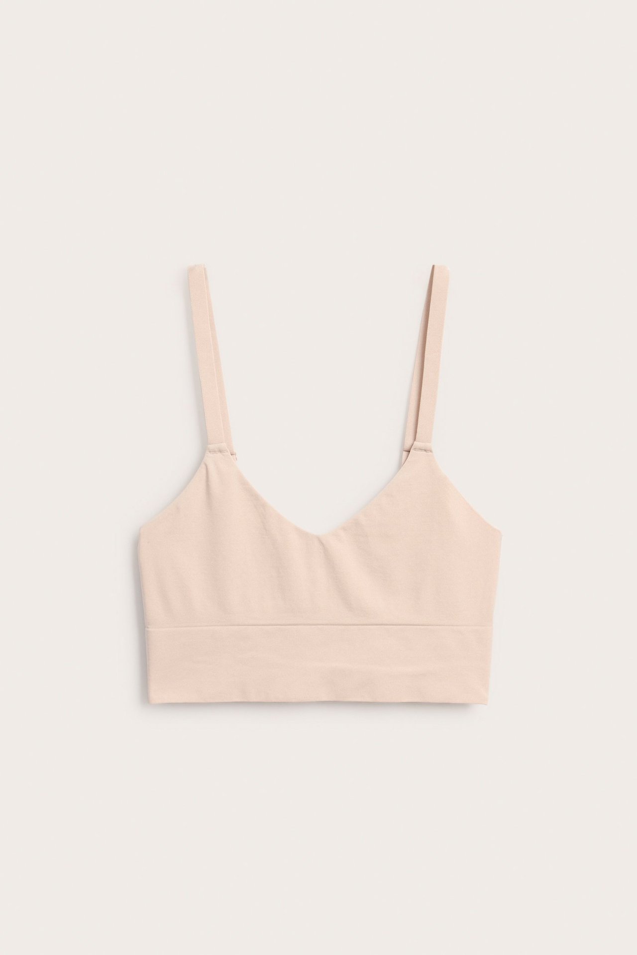 Edestä vaaleanpunainen saumaton toppi-liivi v-kaula-aukolla ja ohuilla säädettävillä olkaimilla.