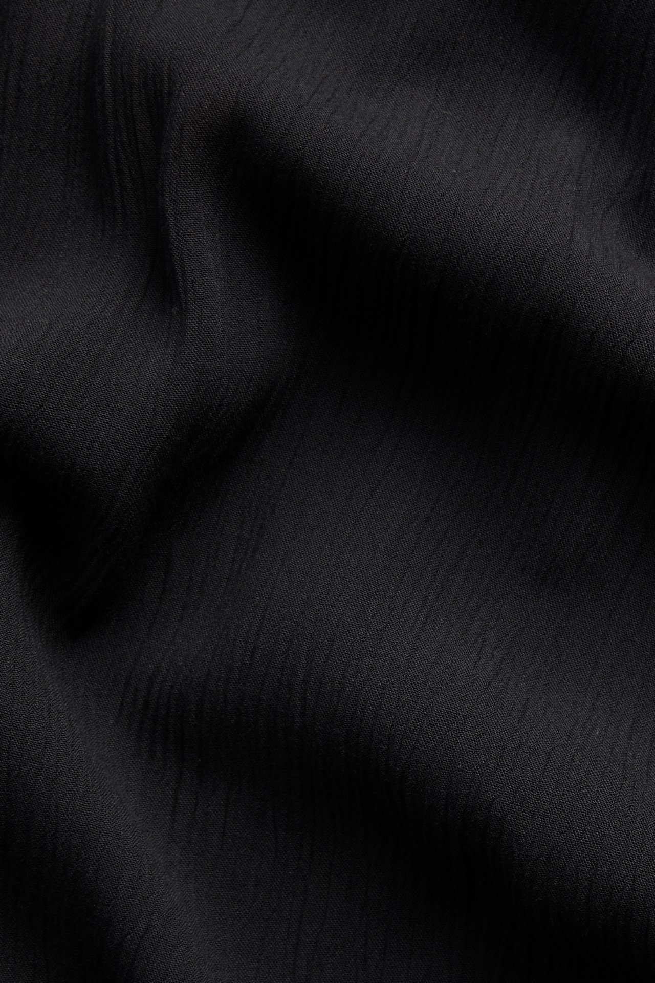 Närbild av svart, krinklat viskostyg, som visar dess avslappnade textur och väv.