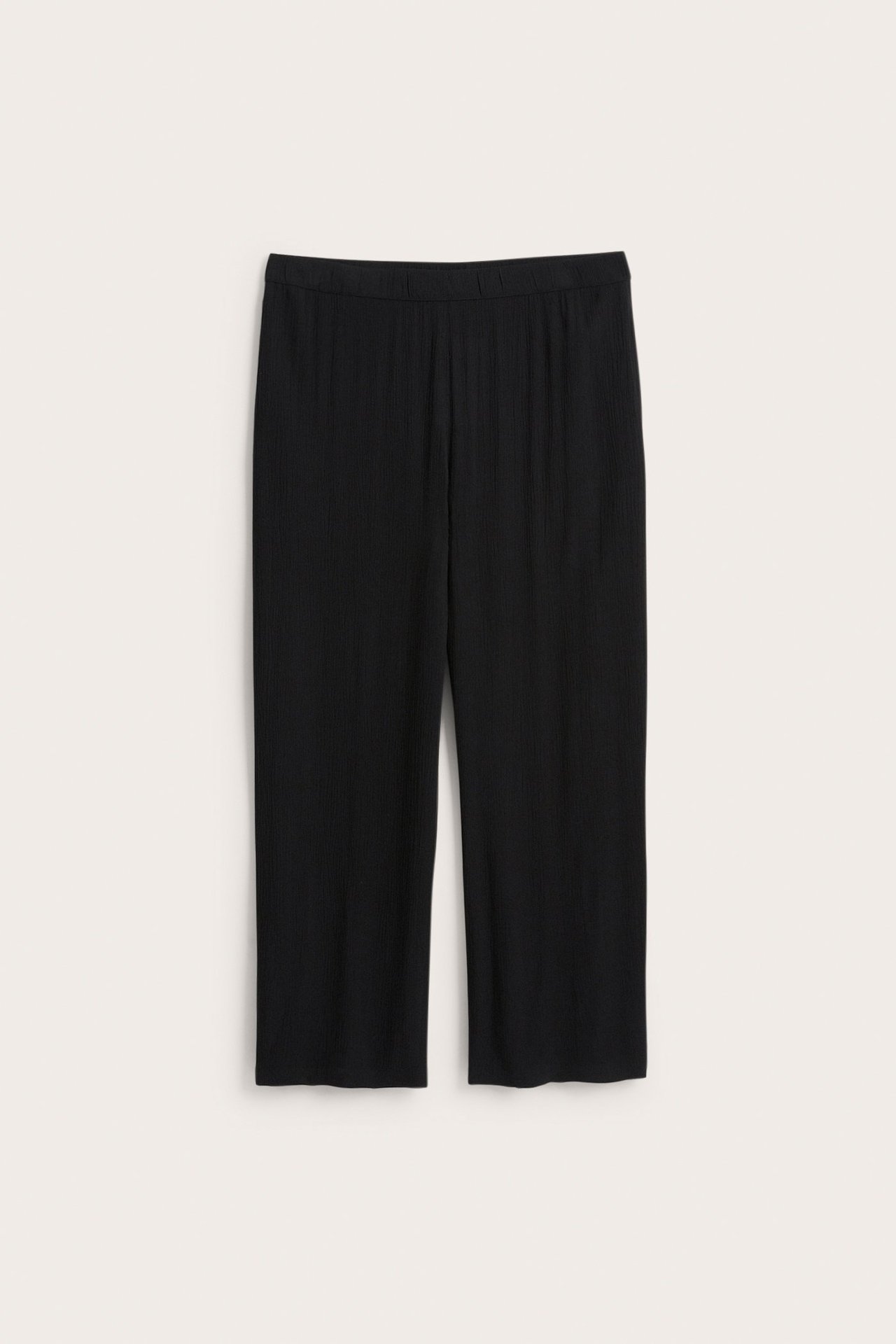 Frontvy av svarta, avslappnade, krinklade vida byxor i viskos med resår i midjan.