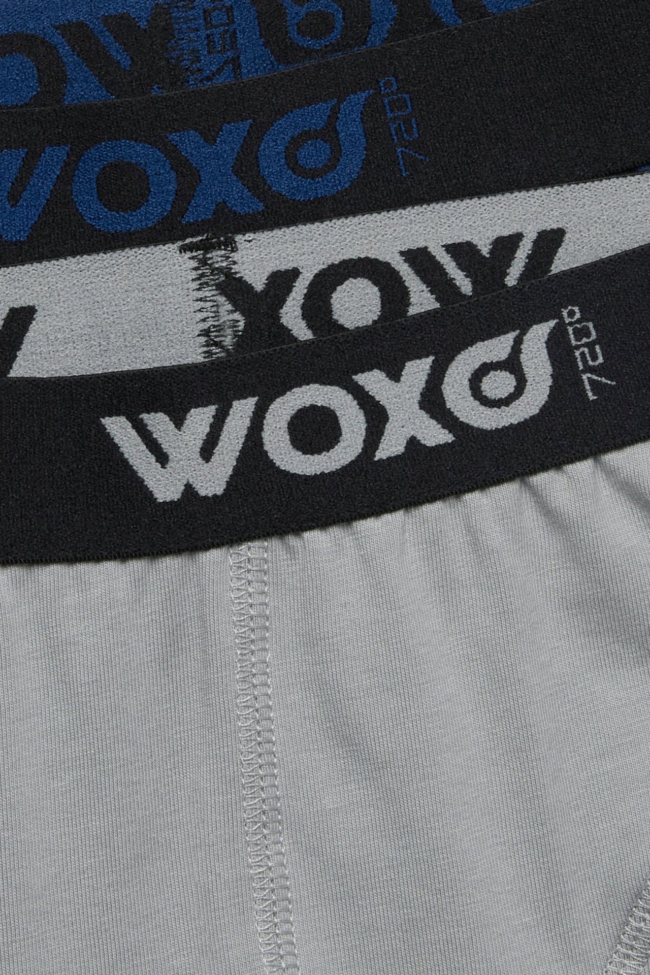 Zbliżenie na trzy bokserki z czarnymi pasami WOXO i korpusami w kolorach granatowym, szarym i jasnoszarym.