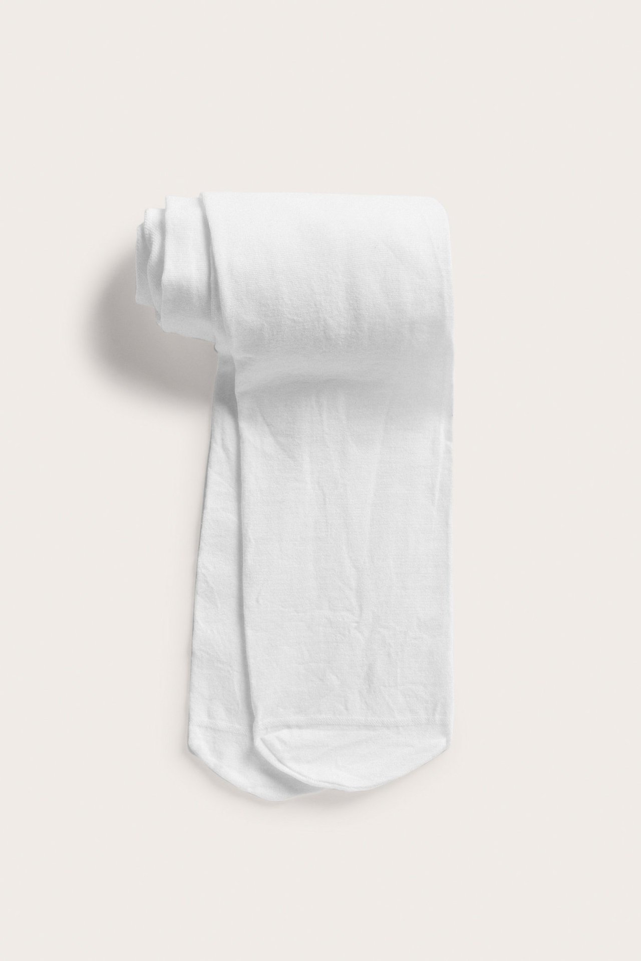 Ylhäältä: valkoiset puuvillasekoitetrikoot, siististi taitettuna.