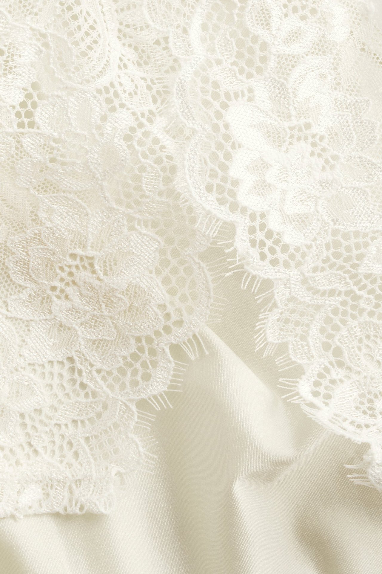 Närbild av offwhite spetsshorts med blommönster och mjukt mikrofibertyg.