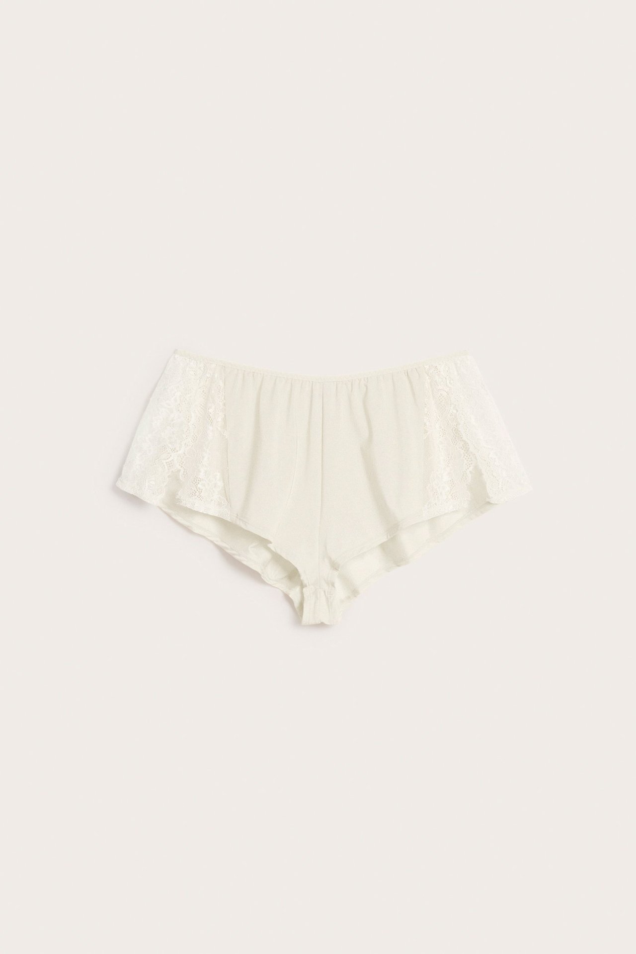 Offwhite shorts har spetsdetaljer på sidorna och en elastisk midja, framifrån.