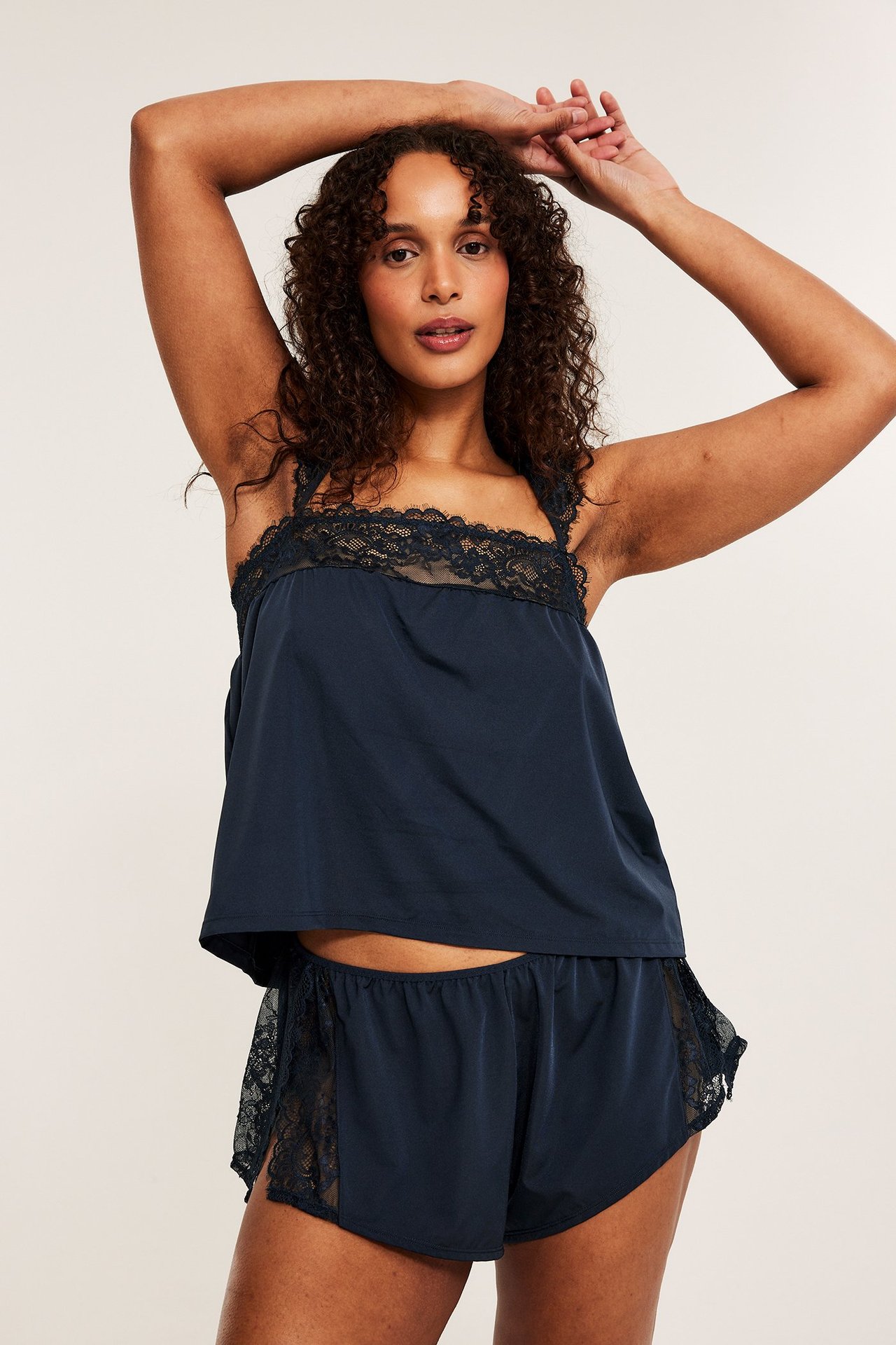 Framifrån: Kvinna i mörkblå spetsshorts med omlottdetalj och matchande spetslinne.