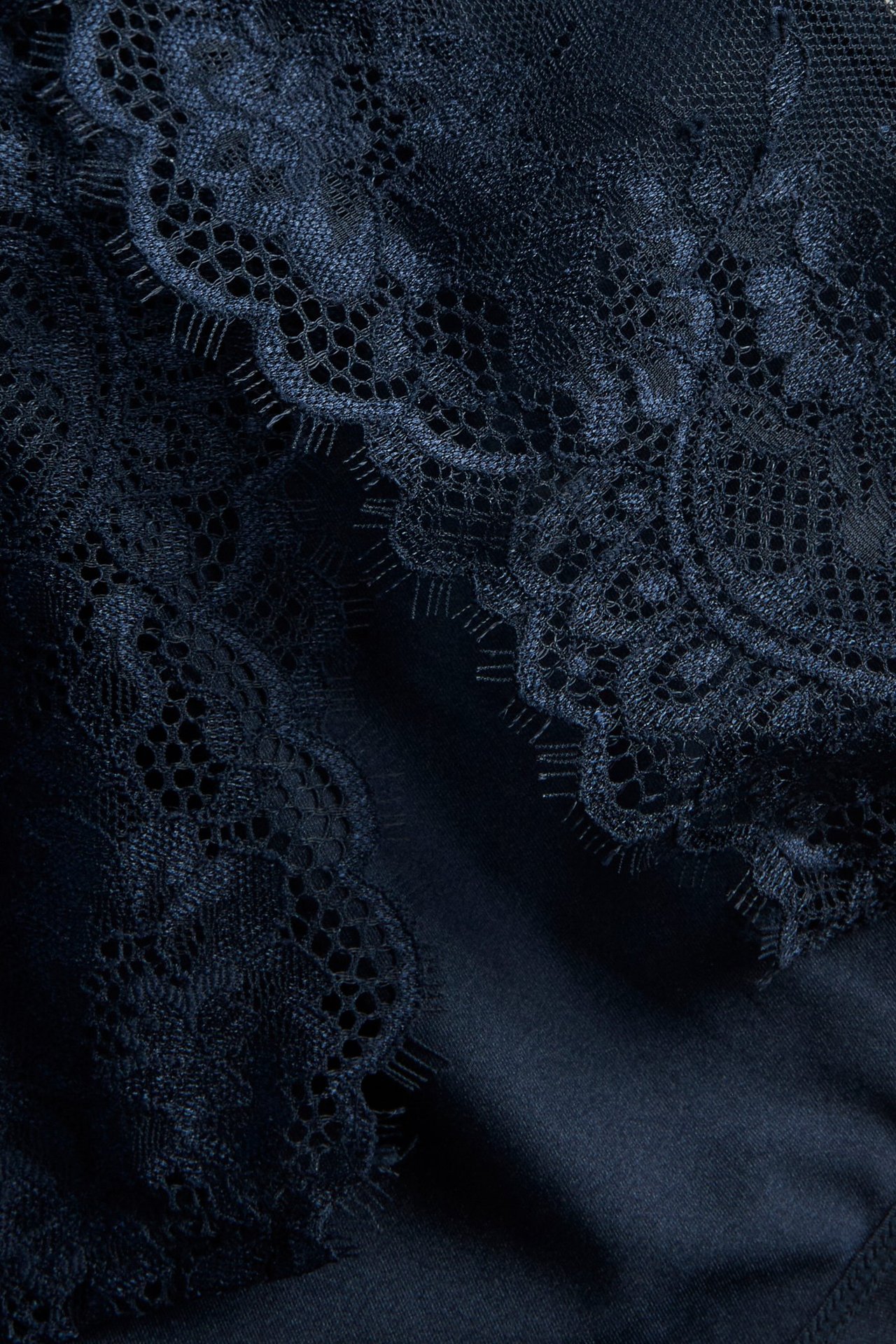 Närbild av mörkblå spetsshorts med mjukt mikrofibertyg och detaljerat spetsmönster.