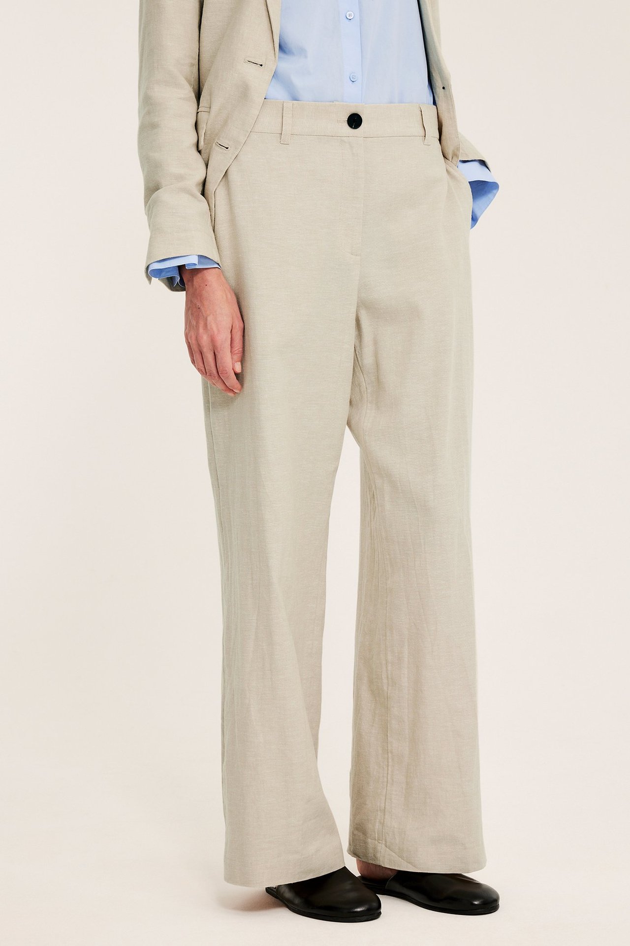Frontvisning: kvinne i beige melert lin-blanding dressbukse, blå skjorte og beige blazer.